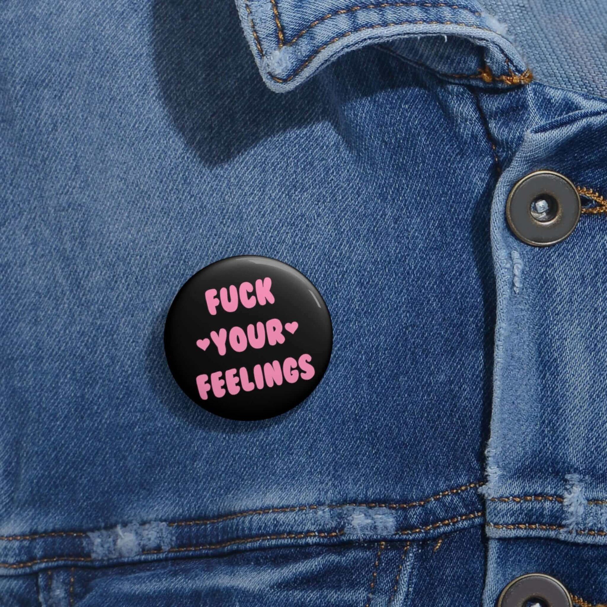 Black pinback button that says Fuck your feelings in pink. 