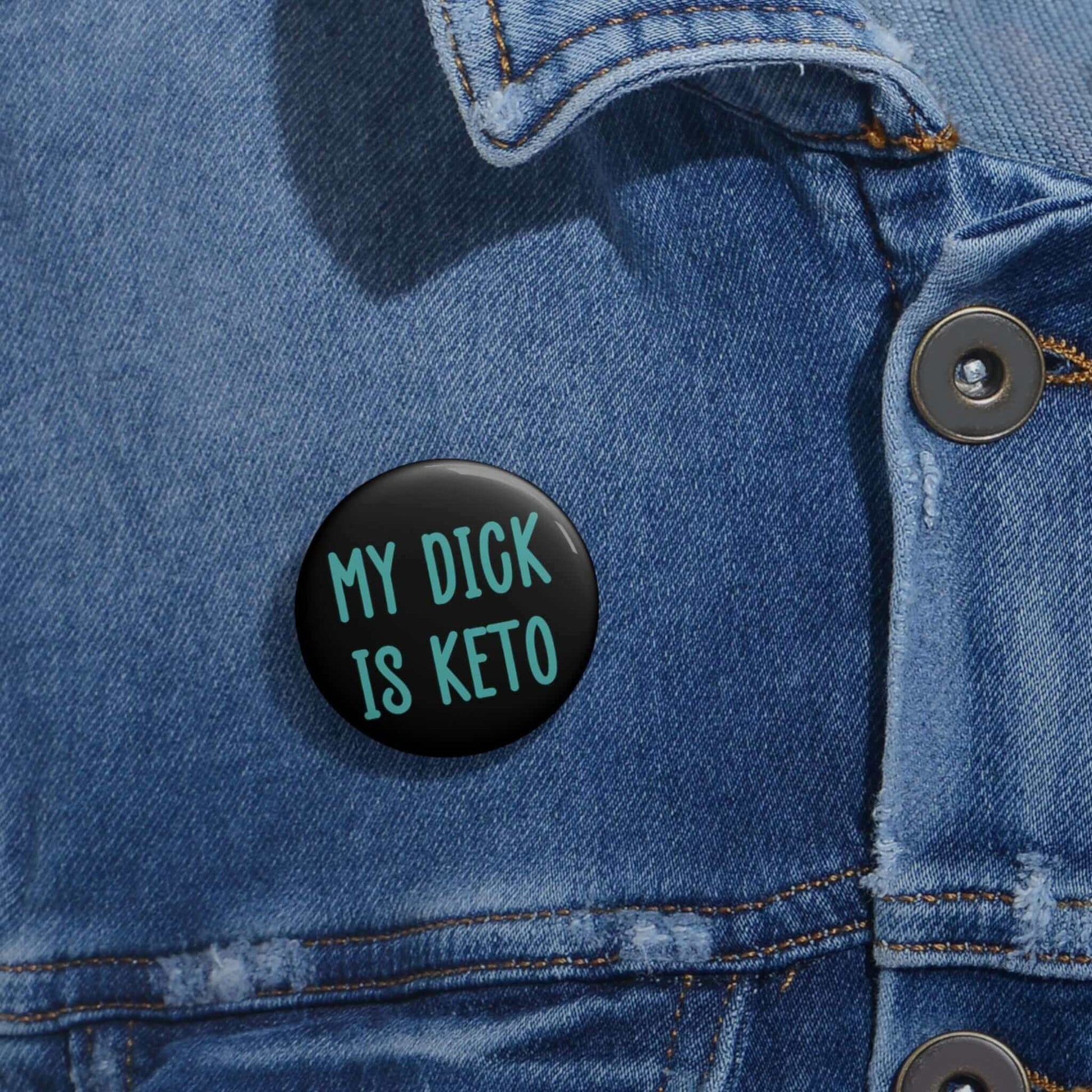 Black pin-back button with the words My dick is keto printed in turquoise font.
