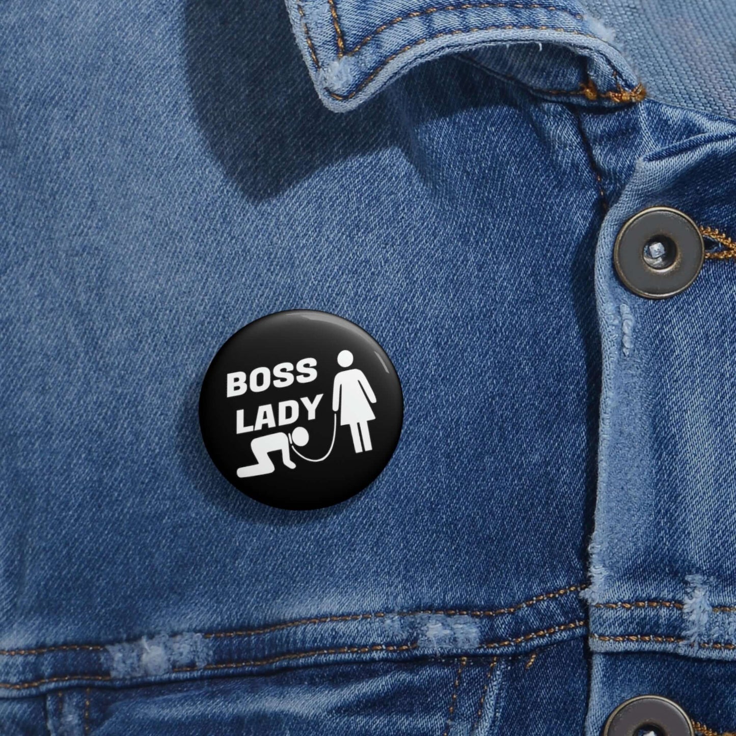 Black pinback button with graphic of collared and leashed man on his hands and knees being led by a woman and the words Boss lady.