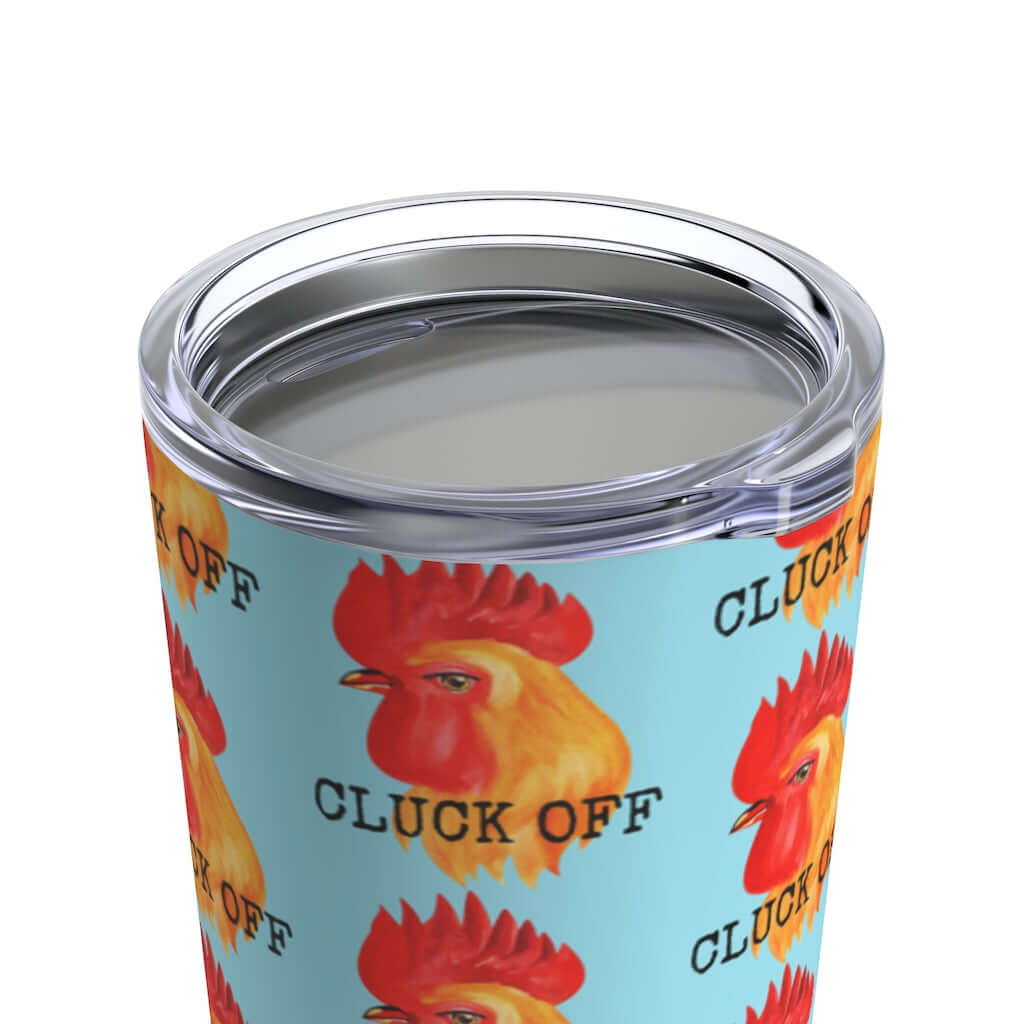 Close up shot of stainless steel travel mug tumbler with clear lid. The tumbler is light blue with graphic of a chicken and the words Cluck off printed all over.