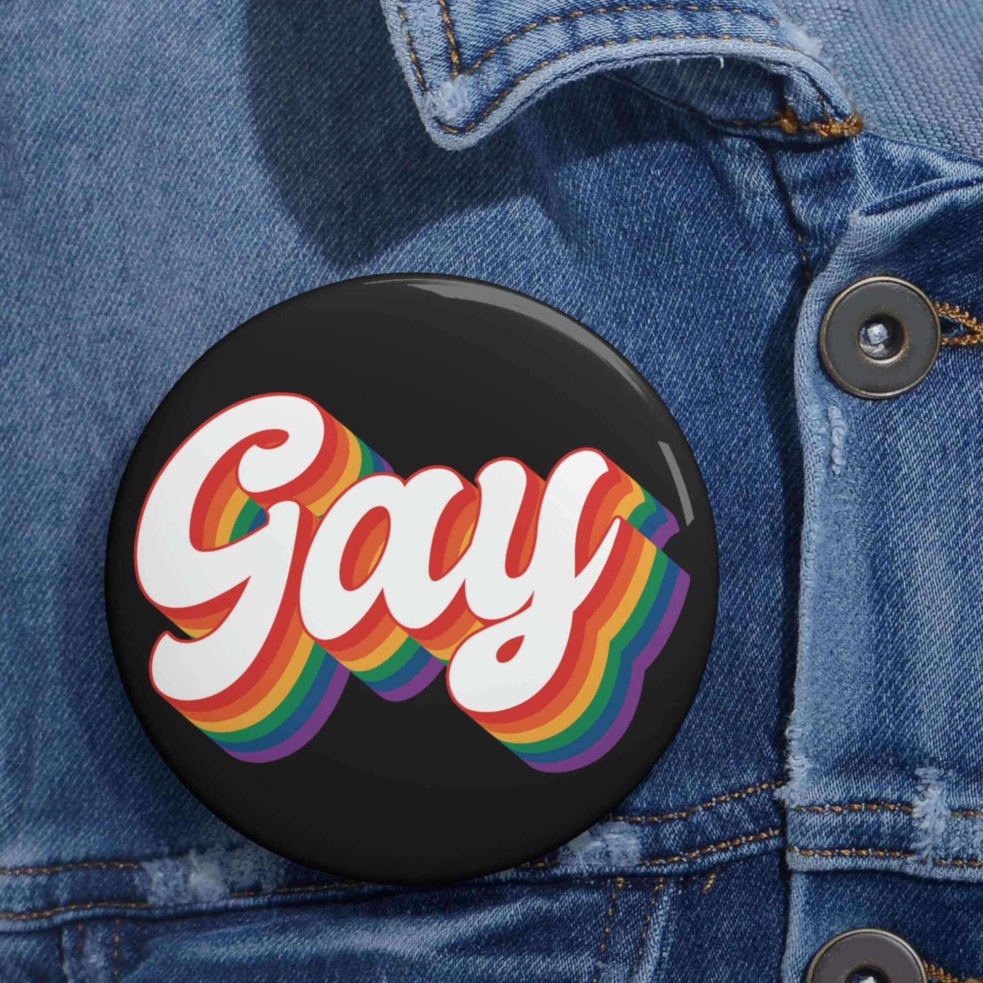 Black pinback button with the word gay in rainbow font.