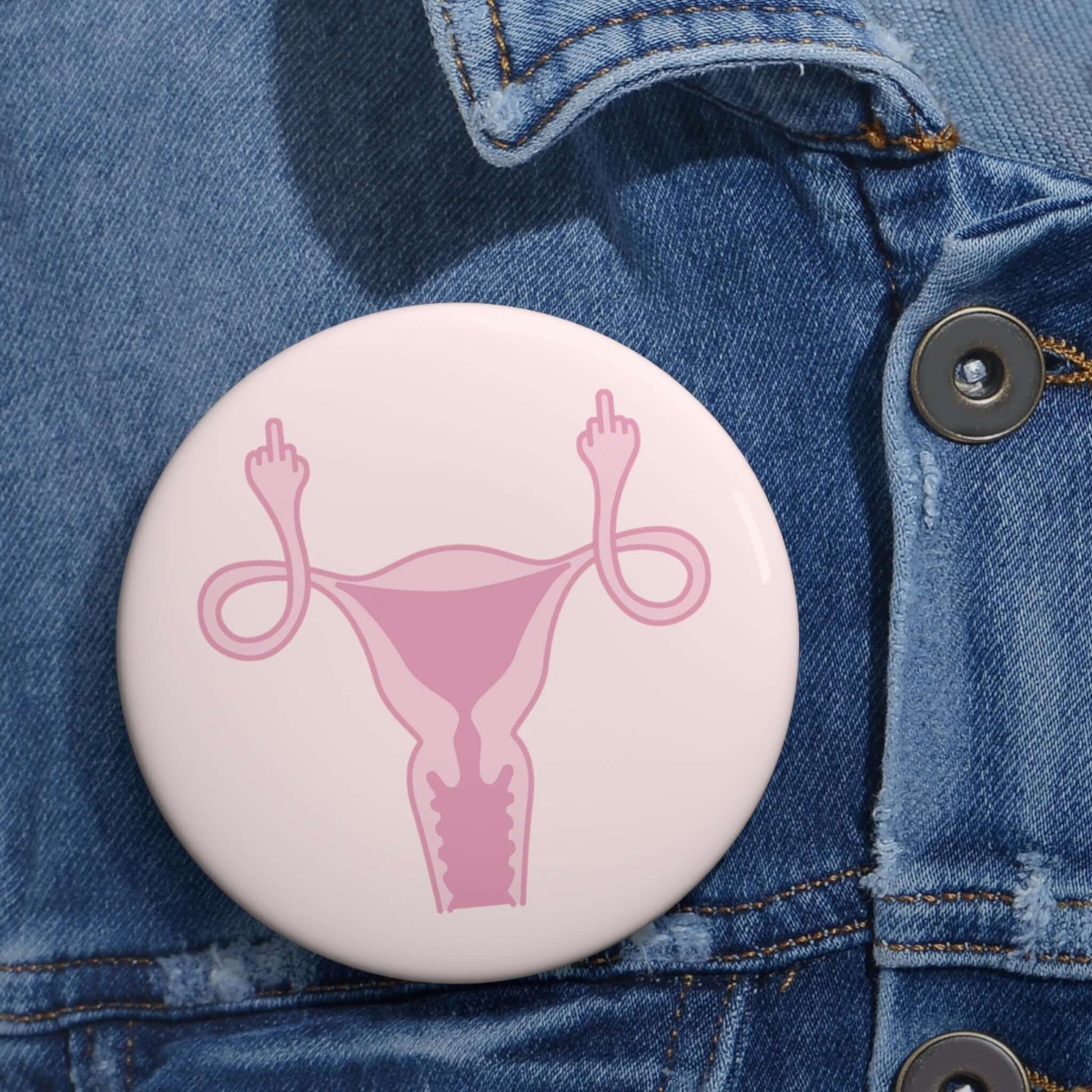 Pink pinback button with image of a uterus flipping the middle finger. 