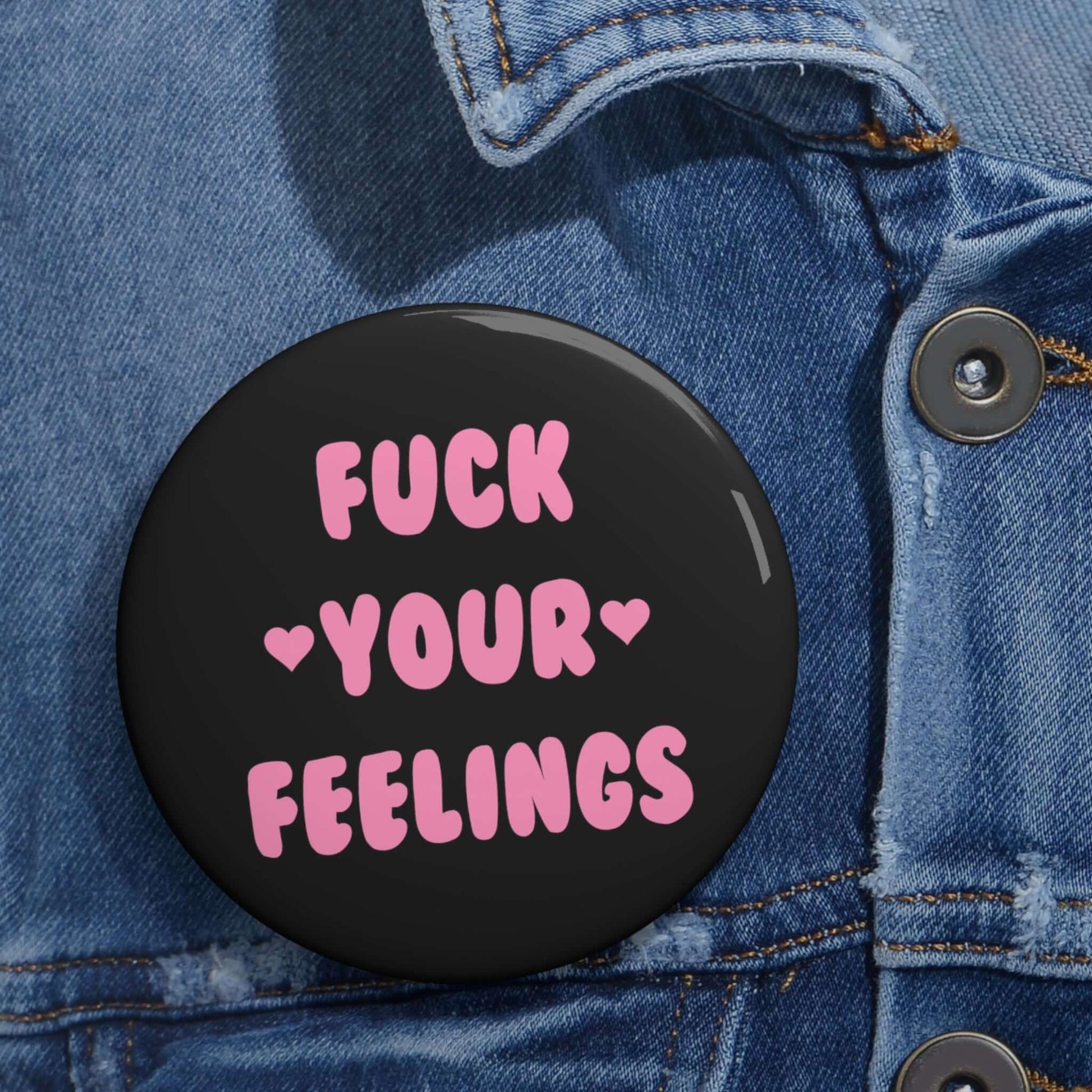 Black pinback button that says Fuck your feelings in pink. 