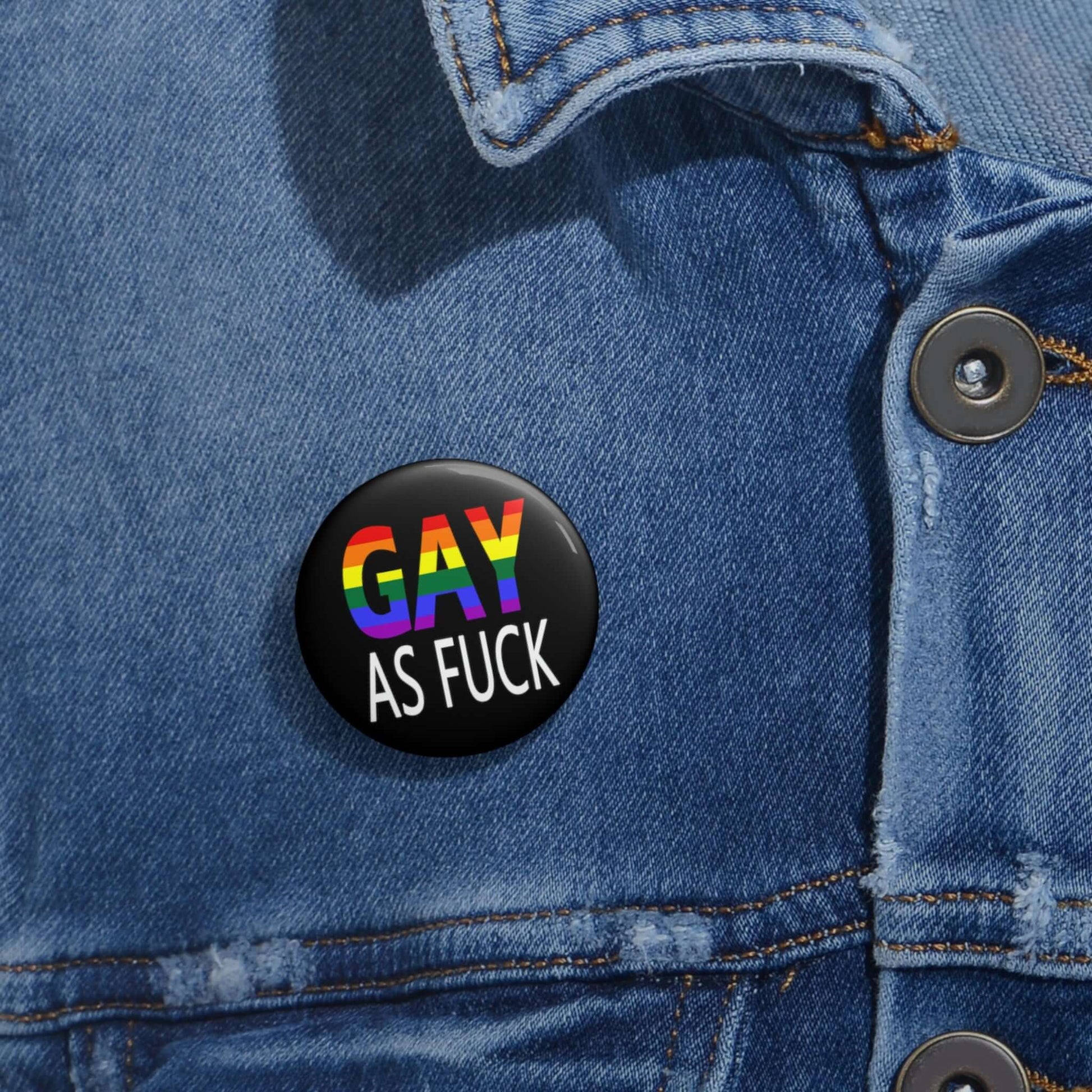 Pin-back button with the words Gay as fuck printed in rainbow font.