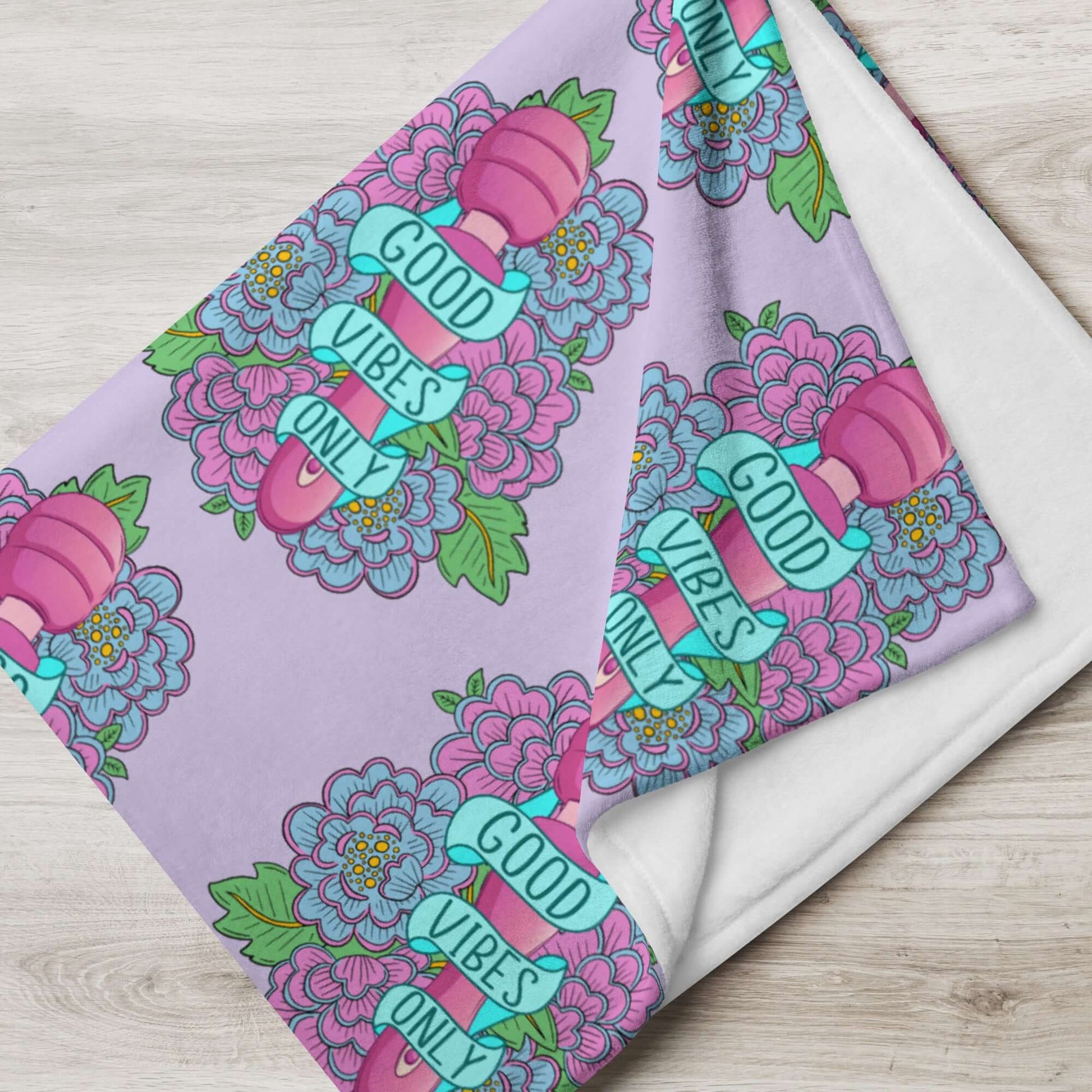 Lavender fleece throw blanket with graphic that has the words Good vibes only layered over a pink wand vibrator with flowers all around. The graphic is repeating all over the blanket.