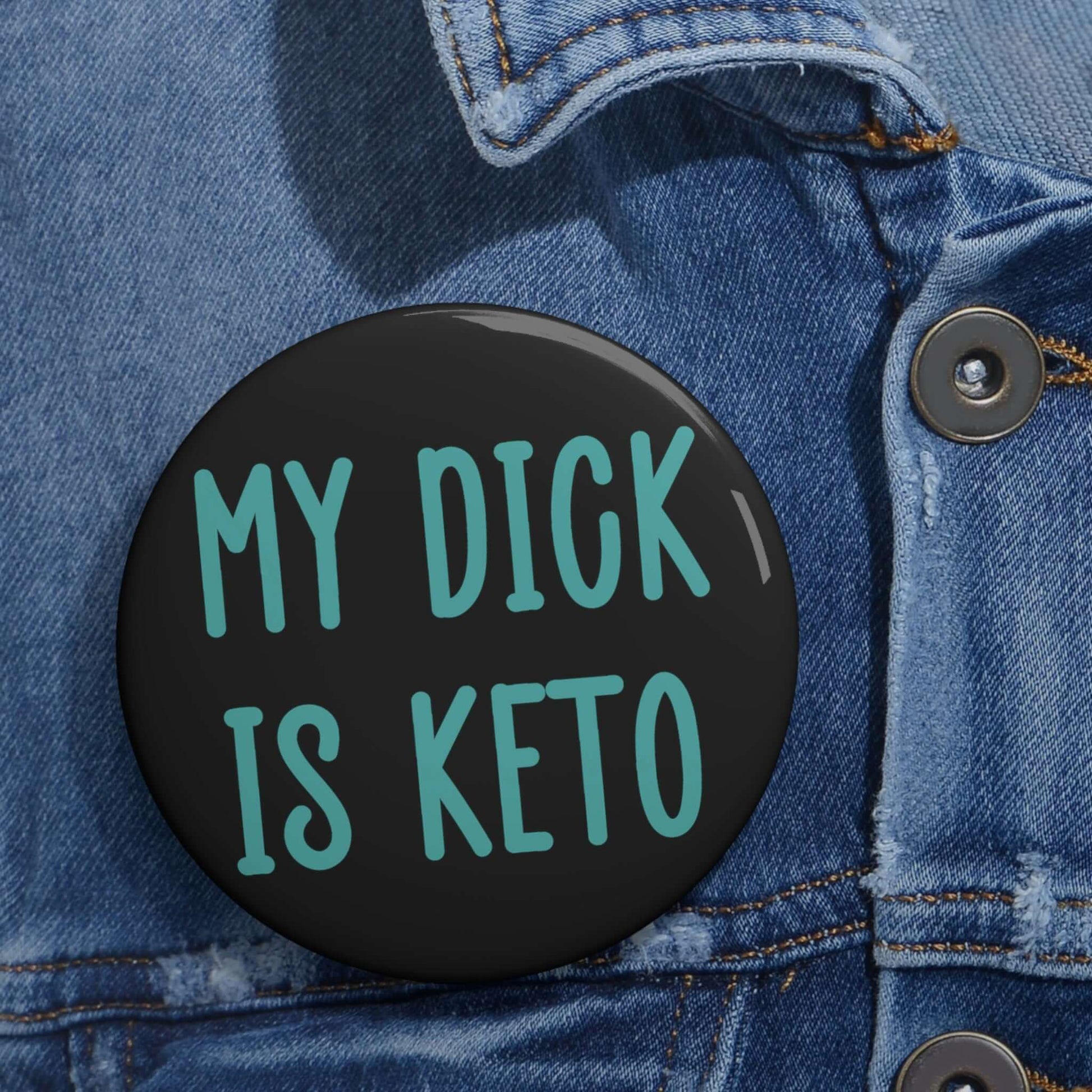 Black pin-back button with the words My dick is keto printed in turquoise font.