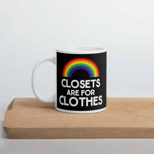 Black and white ceramic coffee mug with a rainbow and the words Clothes are for closets printed on both sides.