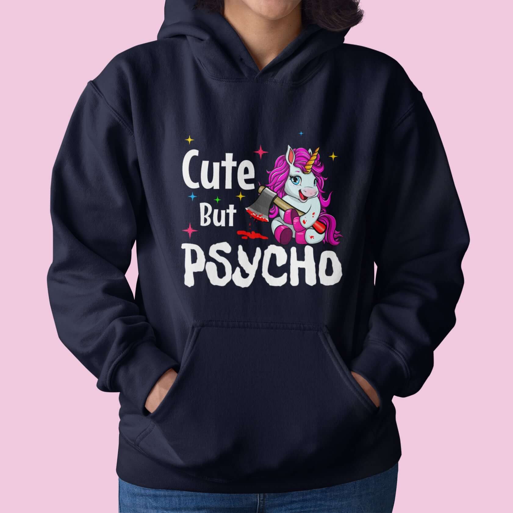 Woman wearing a navy blue hoodie sweatshirt with a graphic of a unicorn holding a knife & the words Cute but psycho printed on the front.