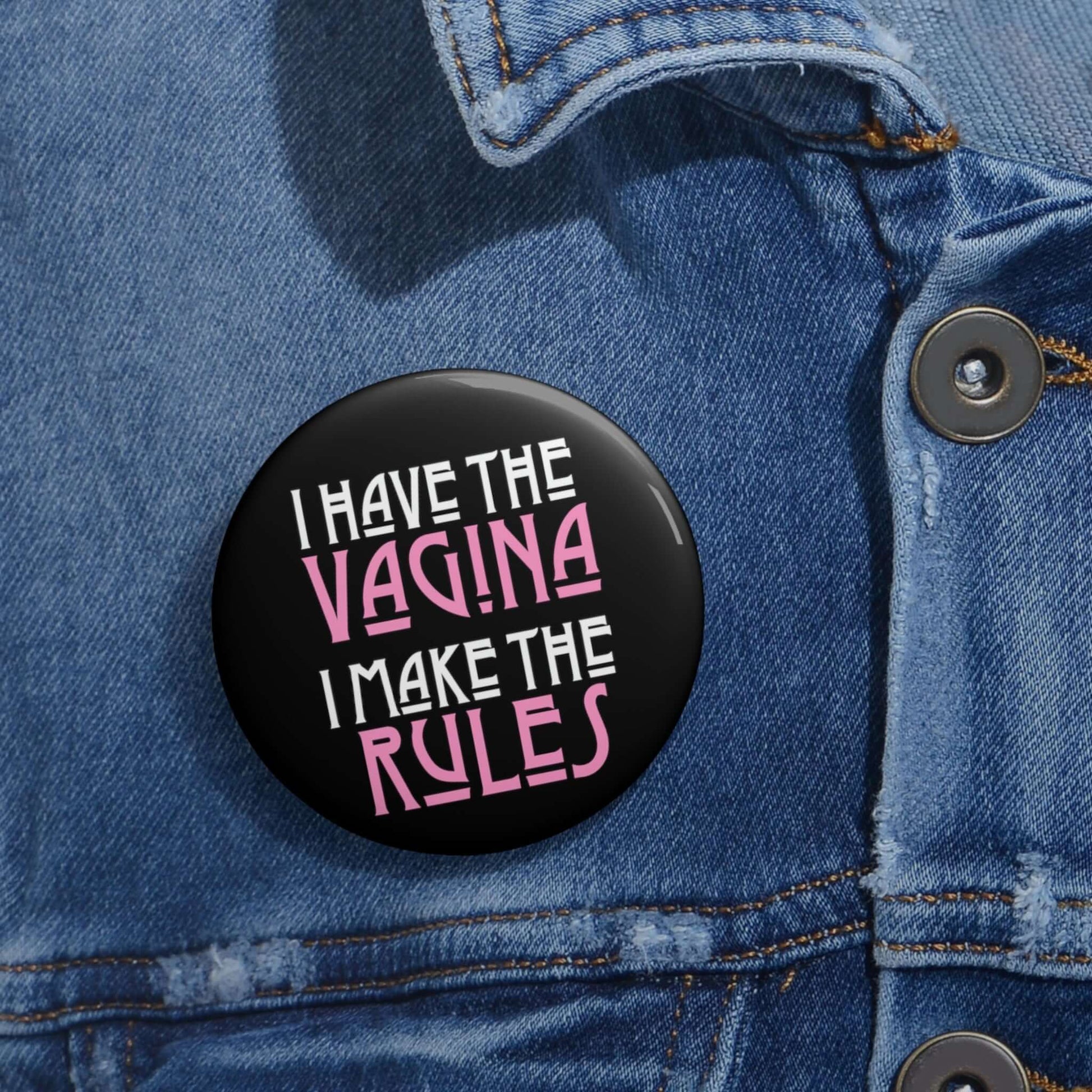 Pinback button that says I have the vagina , I make the rules. The words vagina and rules are pink, the rest of the words are white.