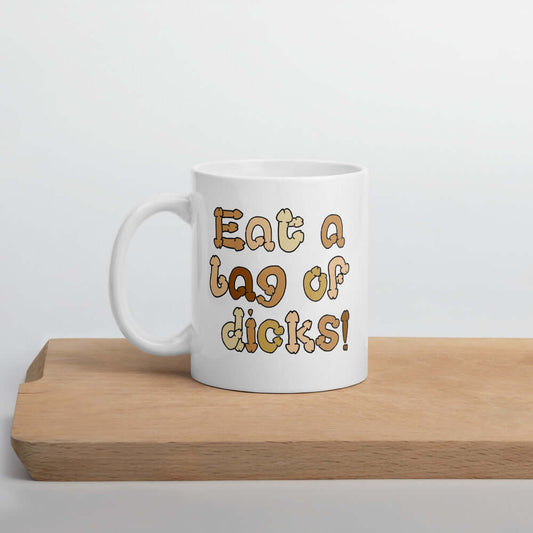 White ceramic coffee mug with the words Eat a bag of dicks printed on both sides. The letters in the words are a penis font and are each a various skin tone.
