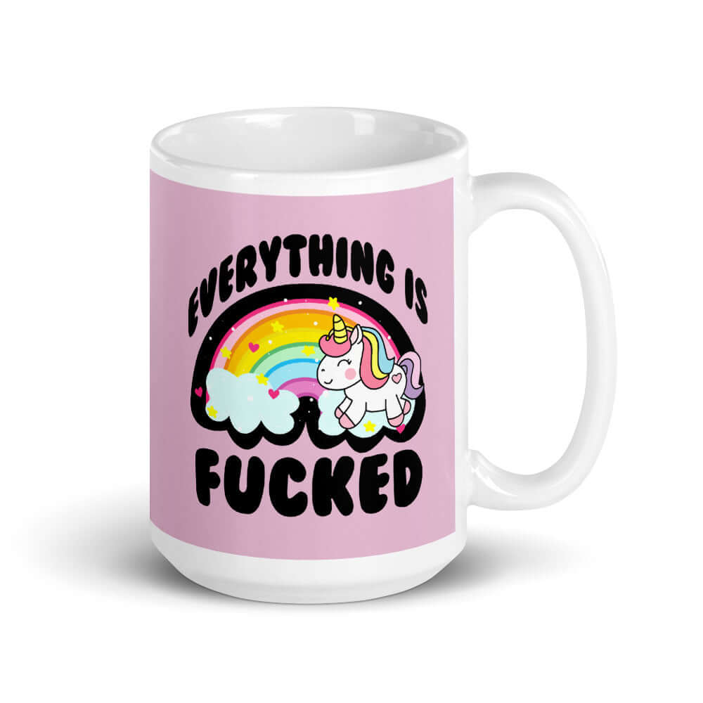 White ceramic coffee mug with a graphic of a kawaii style unicorn and a pastel rainbow with the words Everything is fucked printed on both sides. The background is pink.