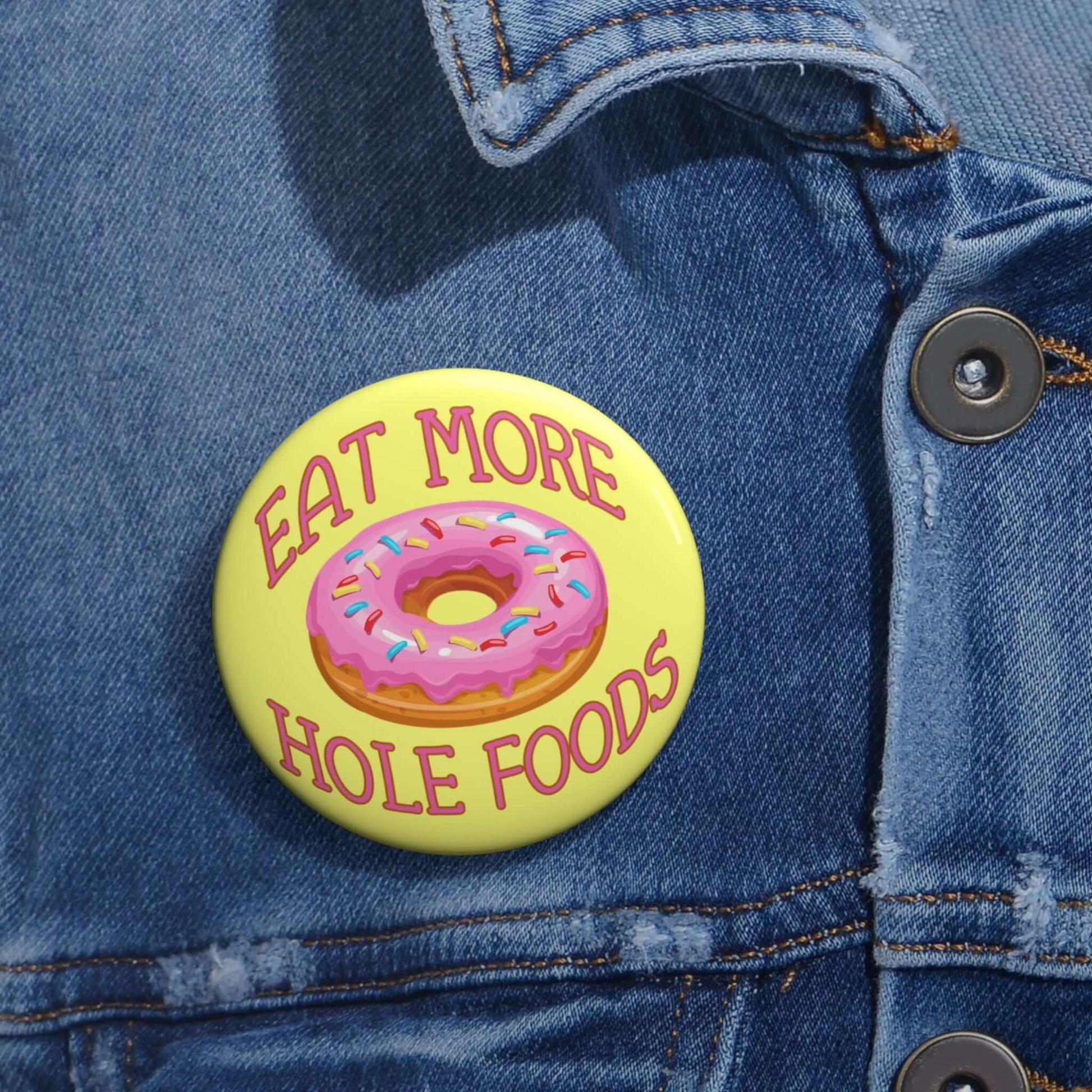 Funny donut pun pinback button with image of a donut with pink icing and sprinkles with the words Eat more hole foods.