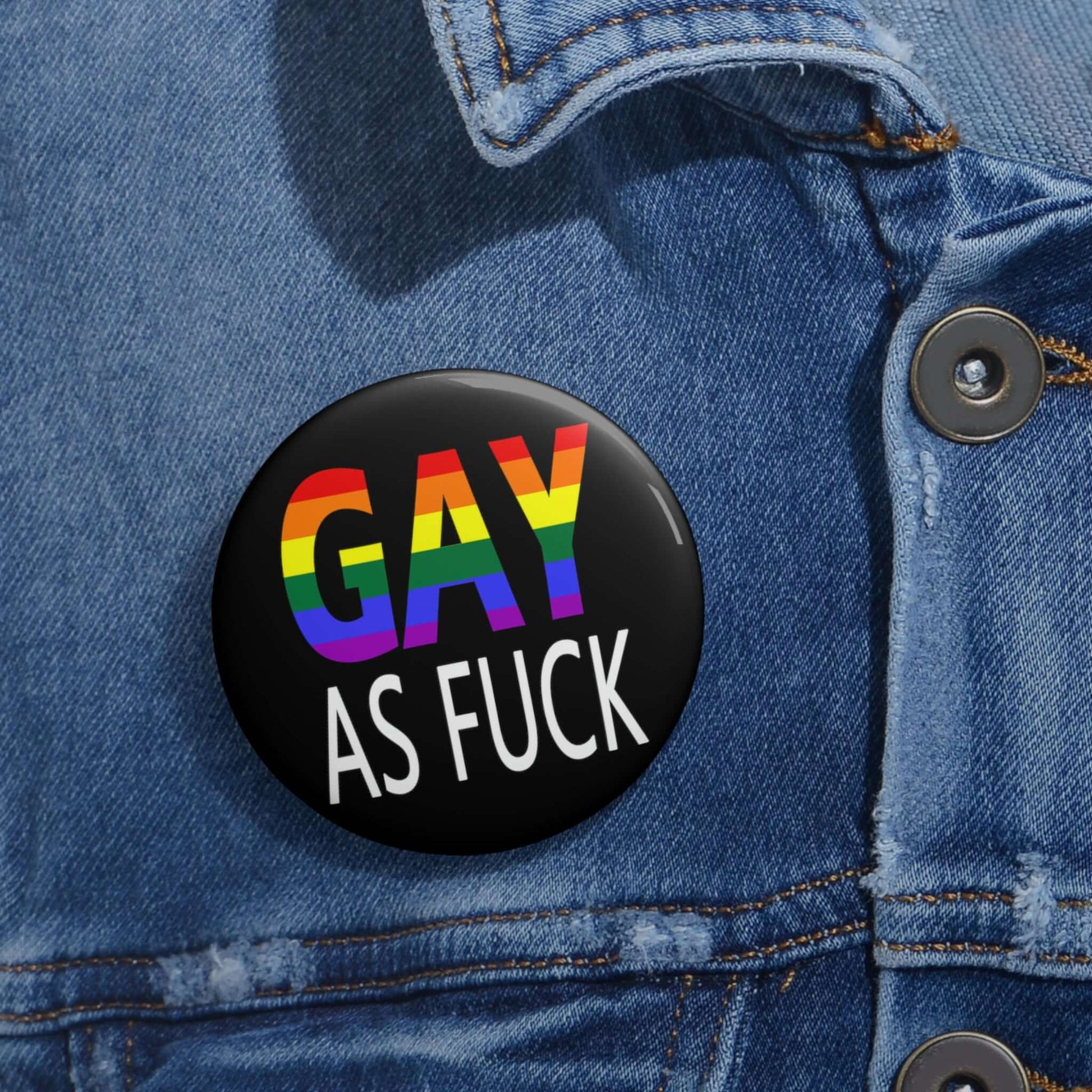 Pin-back button with the words Gay as fuck printed in rainbow font.