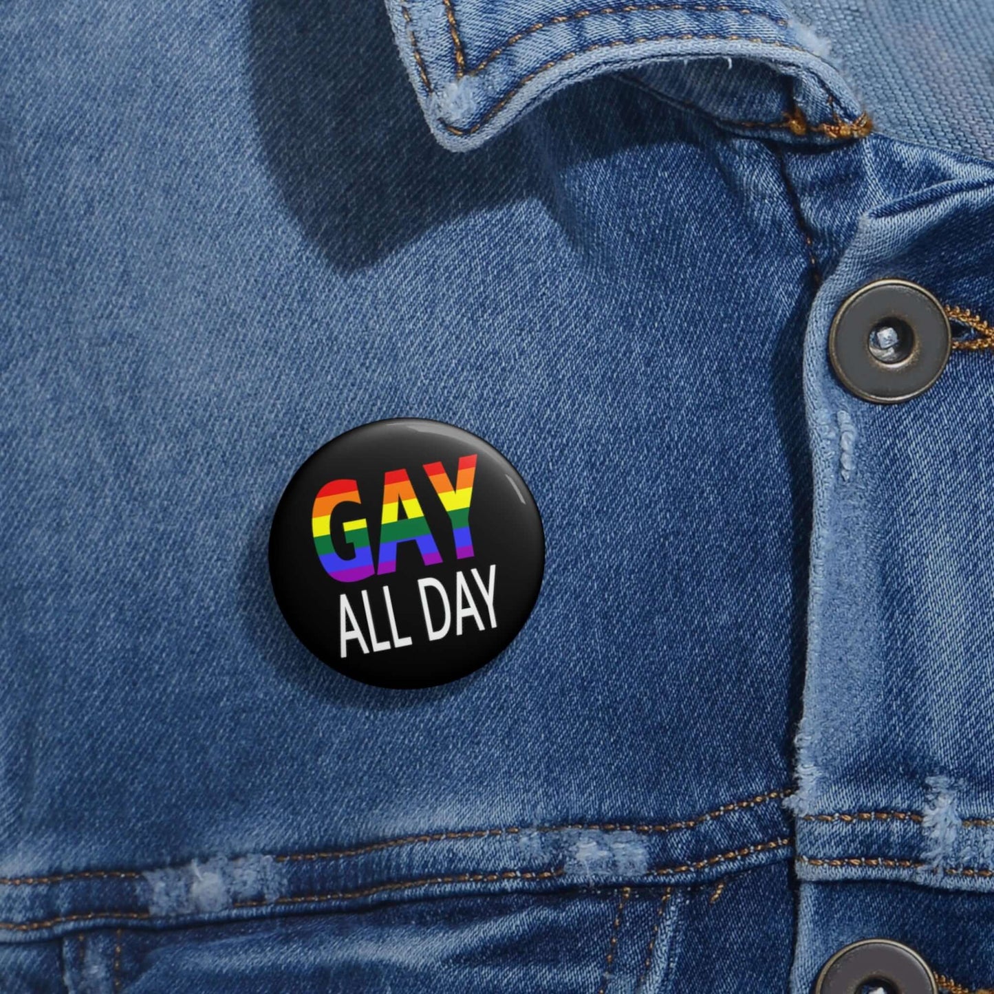 Black pin-back button that says Gay all day in rainbow font.