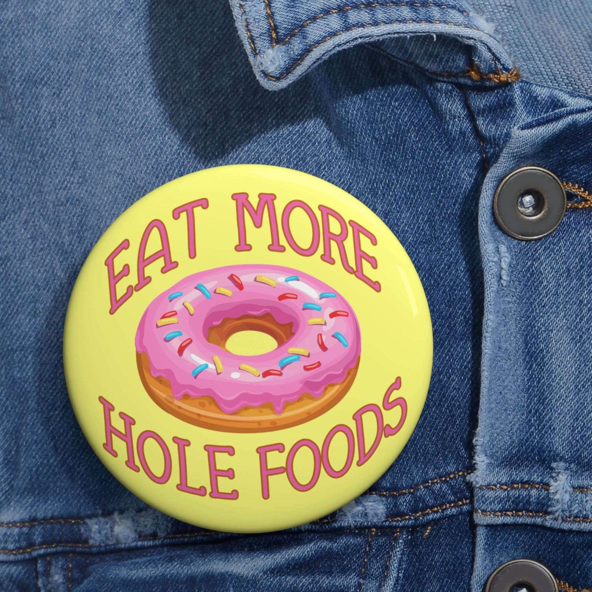 Funny donut pun pinback button with image of a donut with pink icing and sprinkles with the words Eat more hole foods.