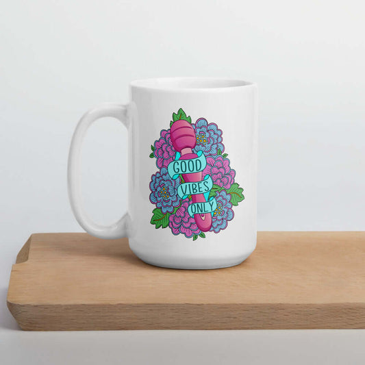 White ceramic coffee mug with graphic that has the words Good vibes only layered over a pink wand vibrator with flowers around. The graphic design is printed on both sides of the mug.