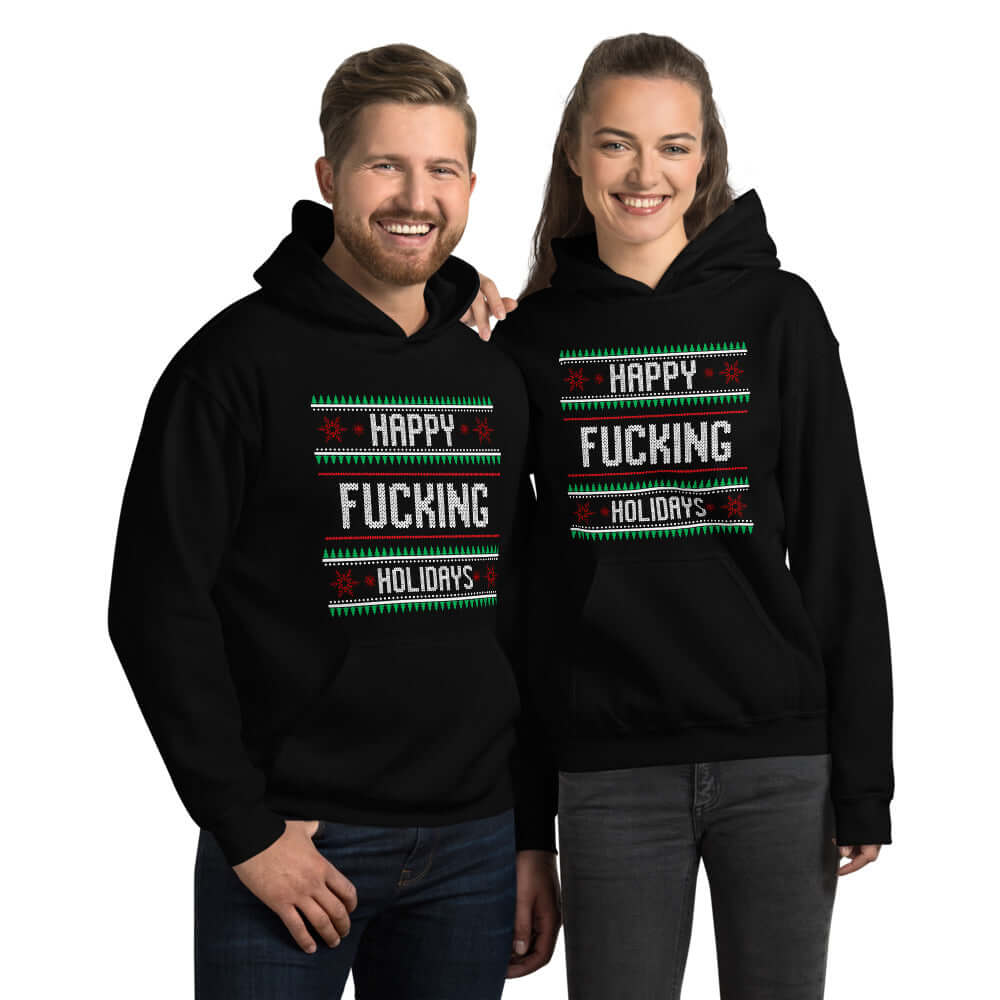 Man and woman standing next to each other wearing a black hoodie sweatshirt with the phrase Happy fucking holidays printed on the front. 