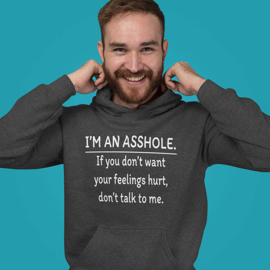 Smiling man wearing a dark grey hoodie sweatshirt with the phrase I'm an asshole. If you don't want your feelings hurt don't talk to me printed on the front.