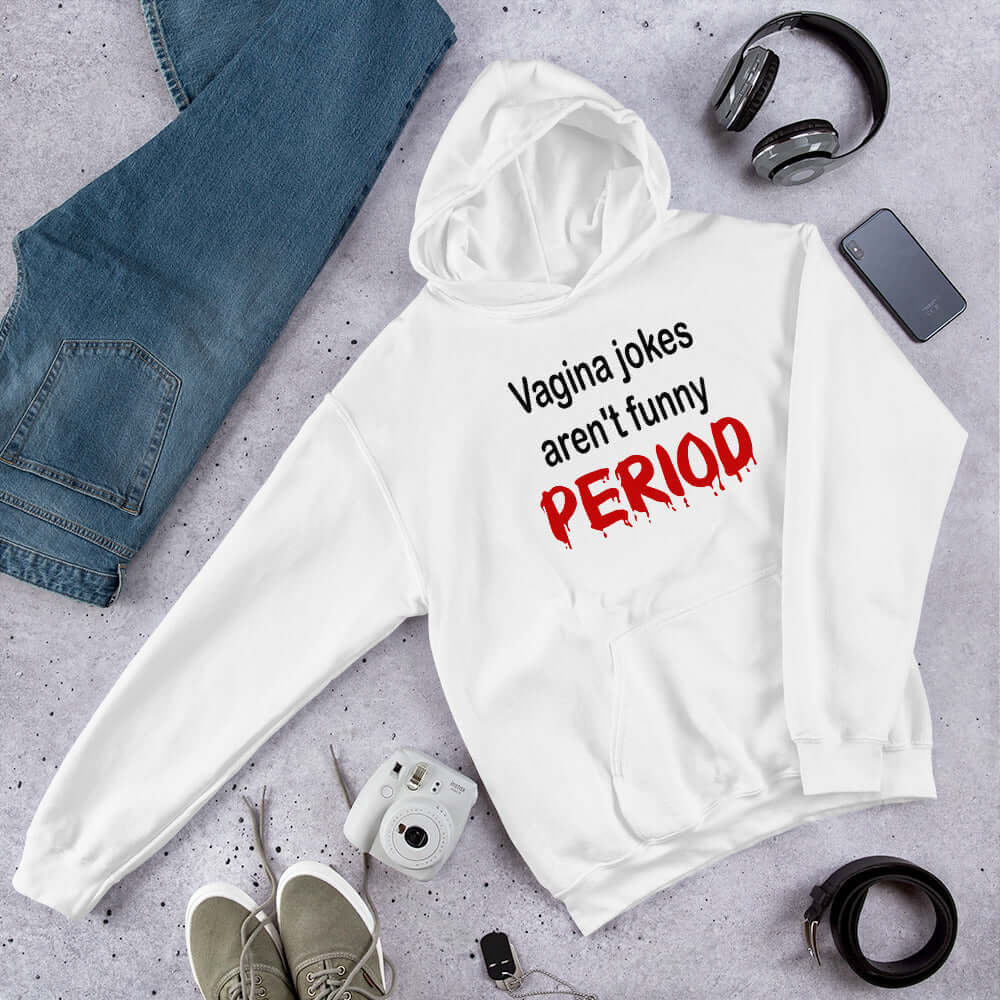 White hoodie sweatshirt with the crude phrase Vagina jokes aren't funny...period. The word period is in a red drippy font. The graphics are printed on the front of the hoodie.