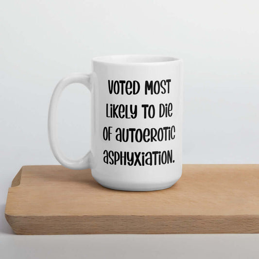 White ceramic coffee mug with the phrase Voted most likely to die of autoerotic asphyxiation printed on both sides.