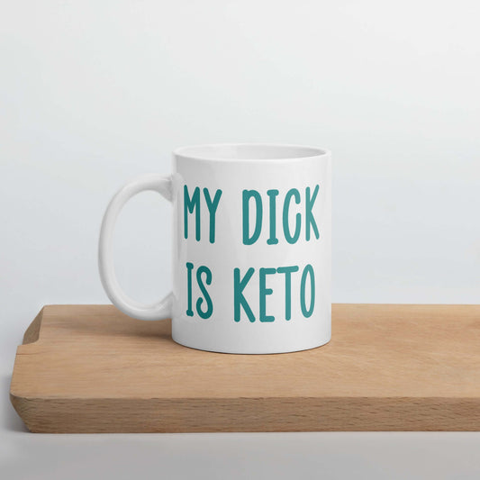 White ceramic coffee mug with the phrase My dick is keto printed on both sides in turquoise font.