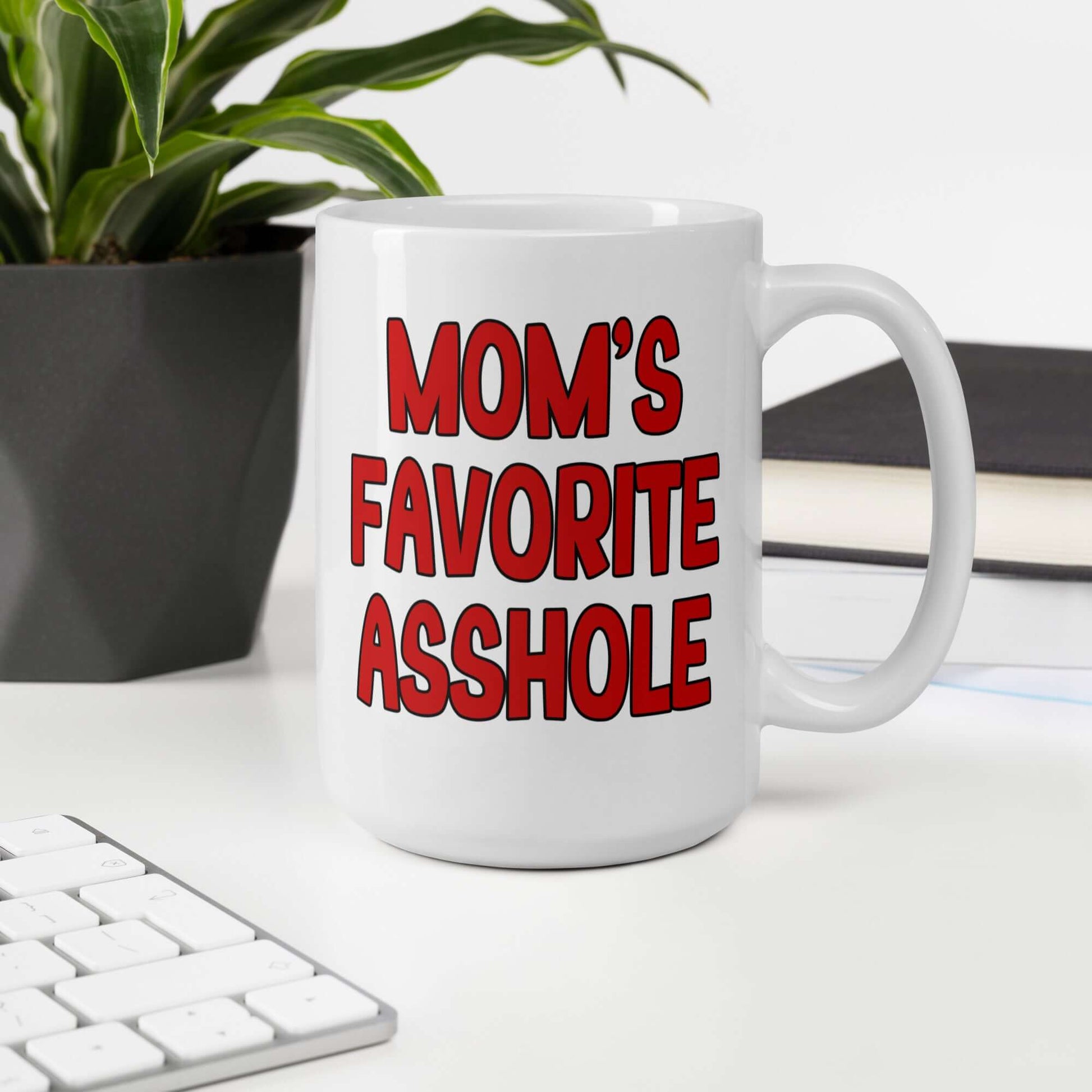 White ceramic mug with the words Mom's favorite asshole printed in red on both sides of the mug.