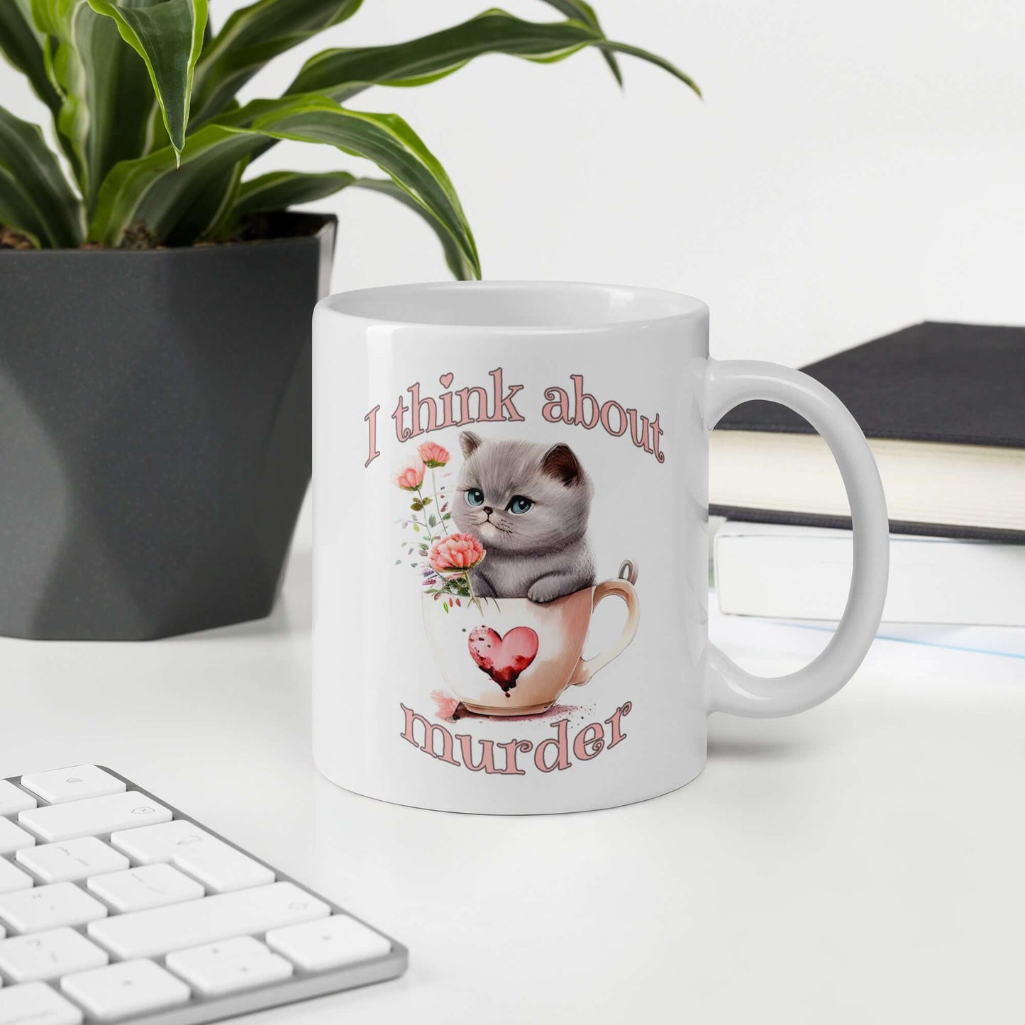 White ceramic mug that says I think about murder with image of cute fluffy kitten sitting in a teacup printed on both sides.