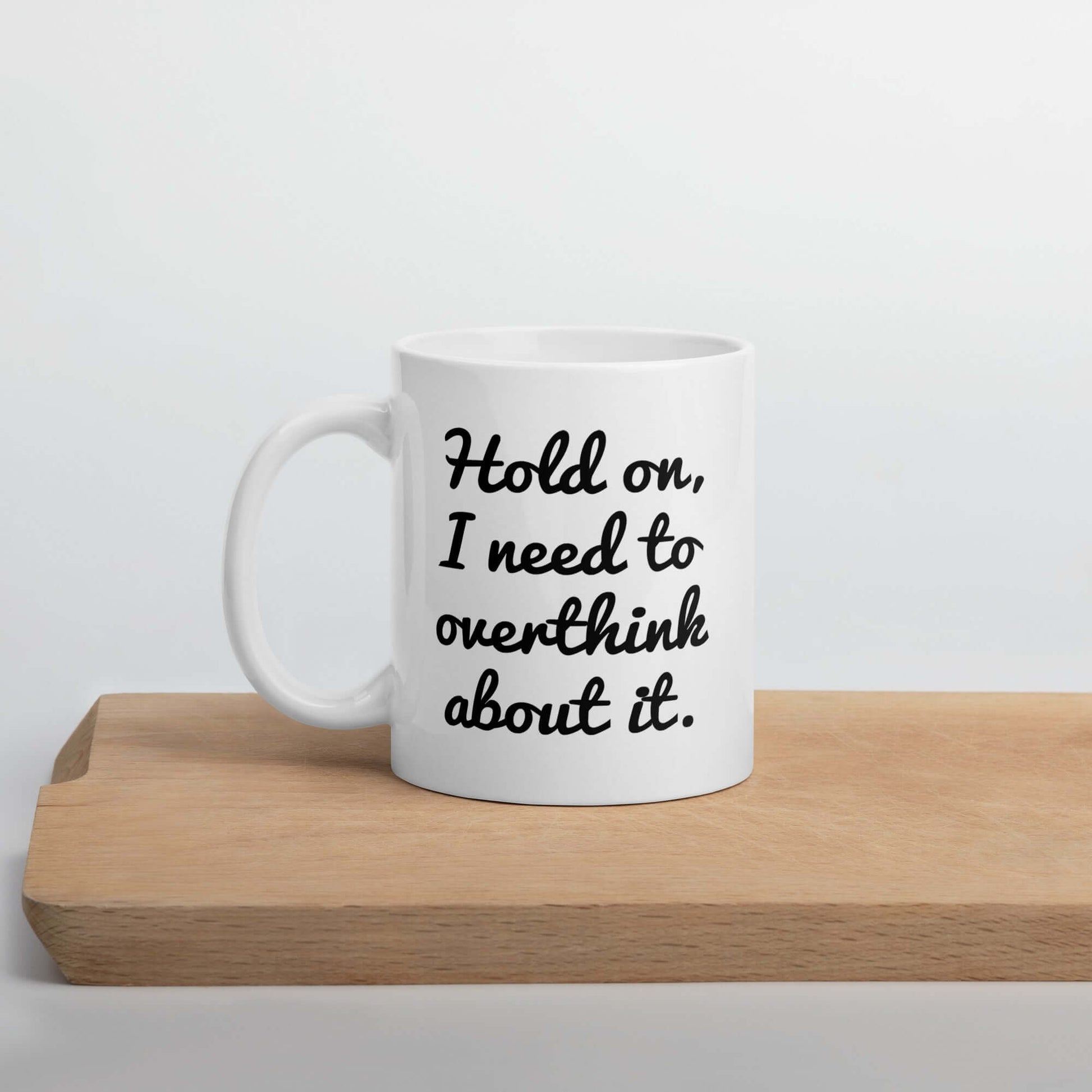 White ceramic coffee mug with the funny phrase Hold on, let me overthink about it printed on both sides of the mug.