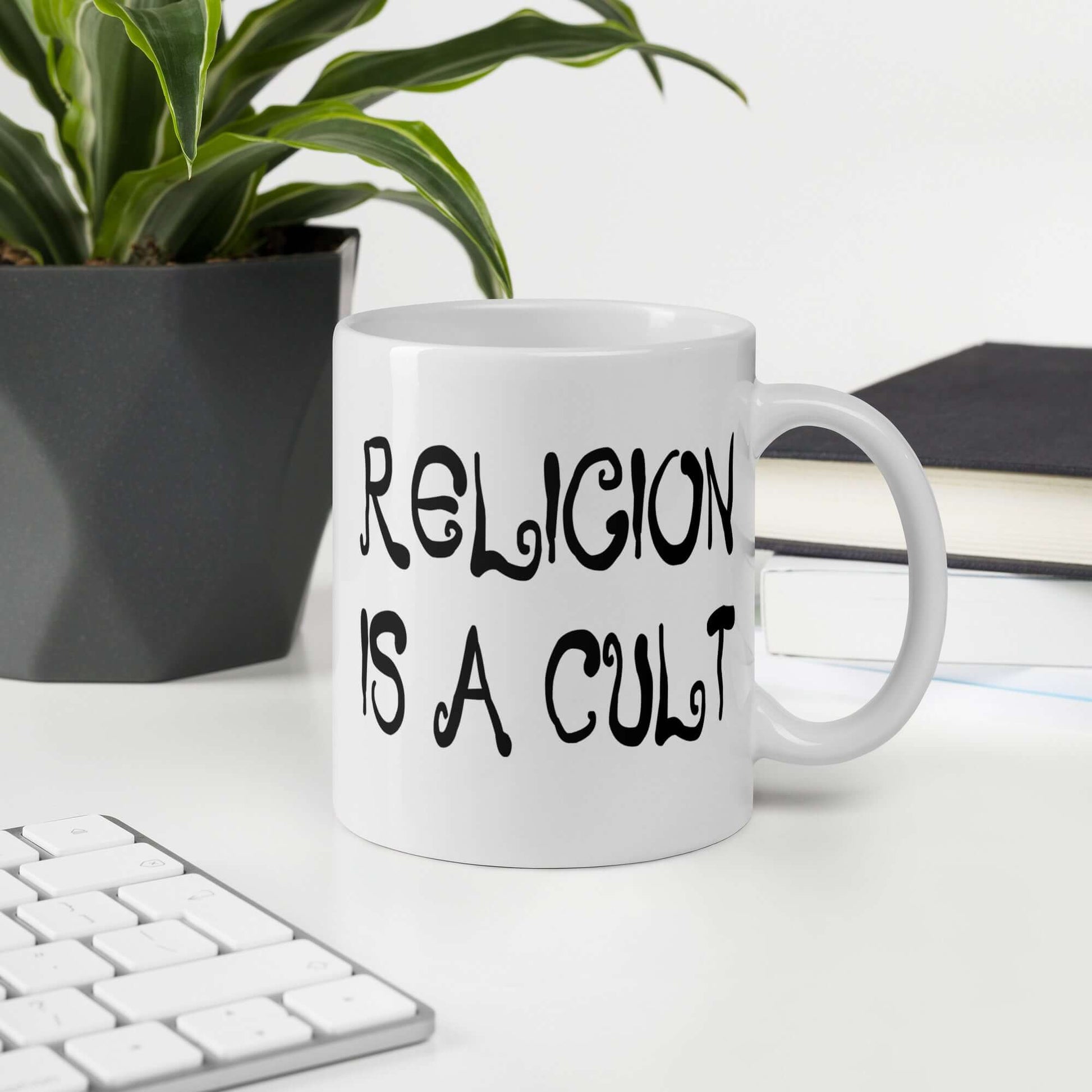 White ceramic coffee mug with the words Religion is a cult printed on both sides.