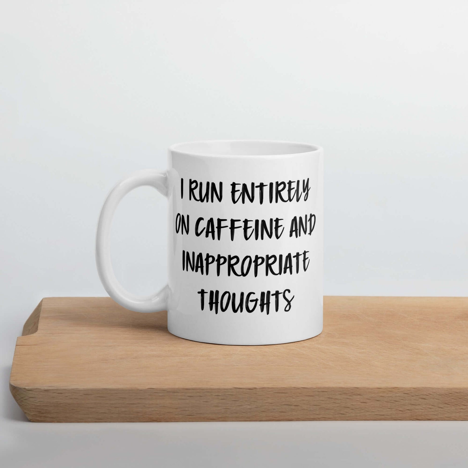 White ceramic coffee mug with the words I run entirely on caffeine & inappropriate thoughts printed on both sides.