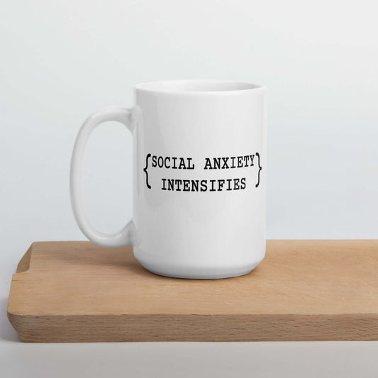 White ceramic coffee mug with the words Social anxiety intensifies printed on both sides.