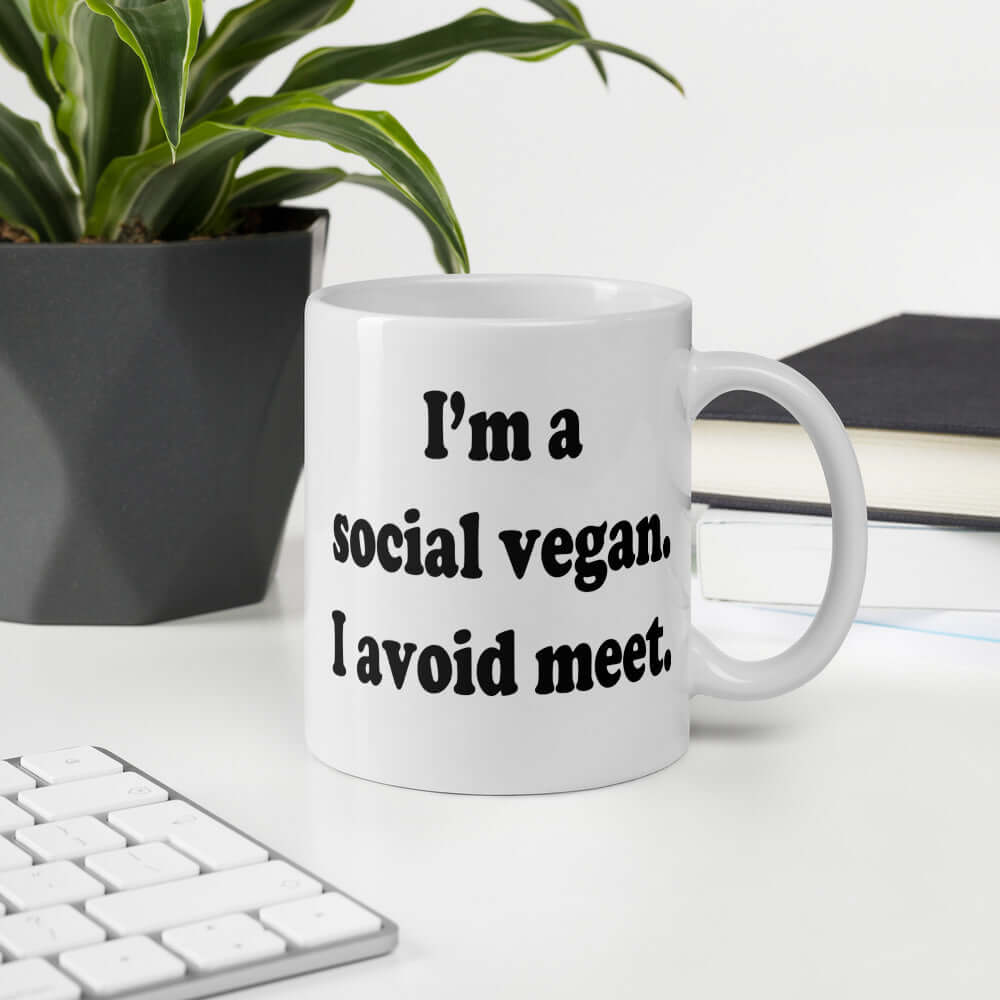 White ceramic coffee mug with the pun phrase I'm a social vegan, I avoid meet printed on both sides.