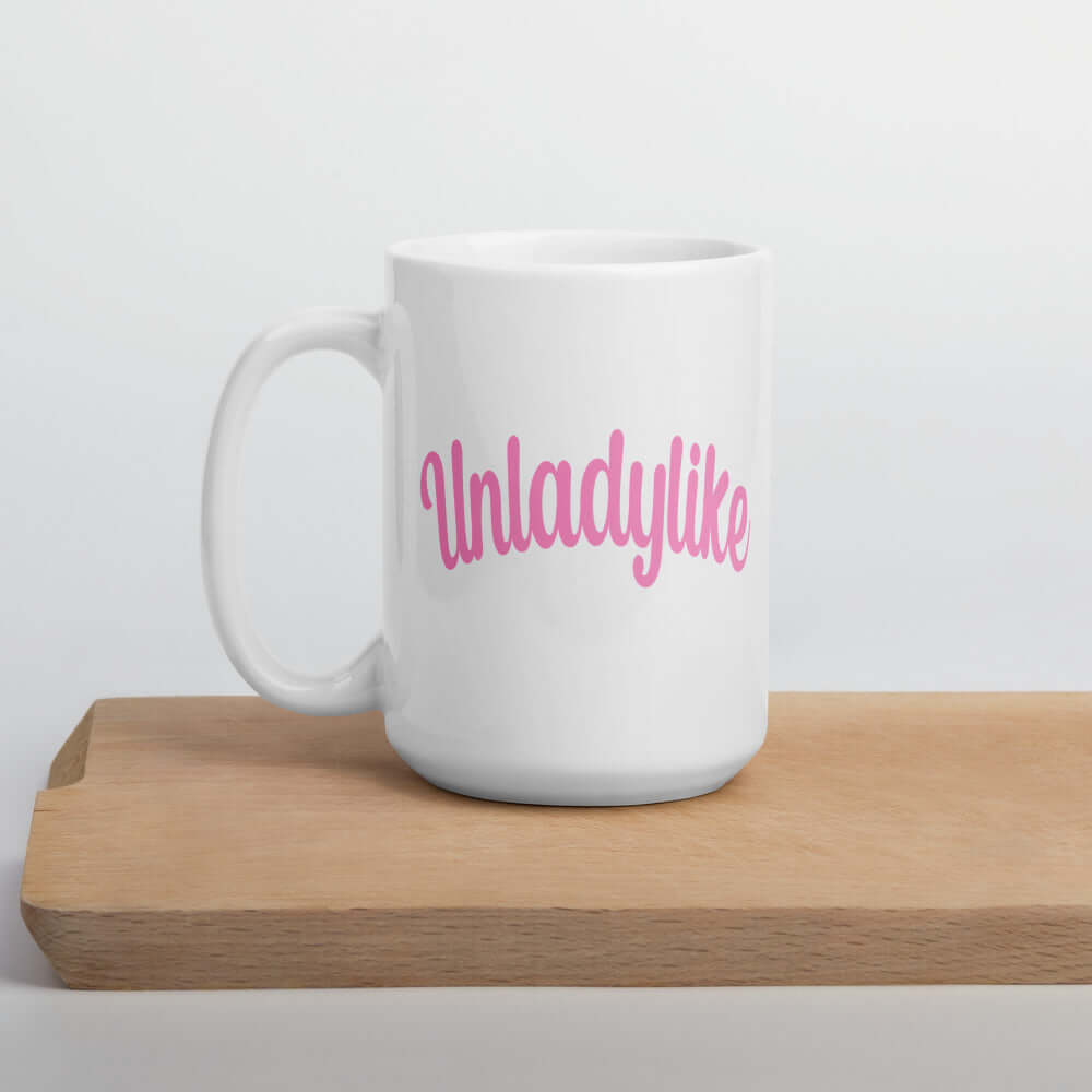 White ceramic coffee mug with the word Unladylike printed in pink on both sides.