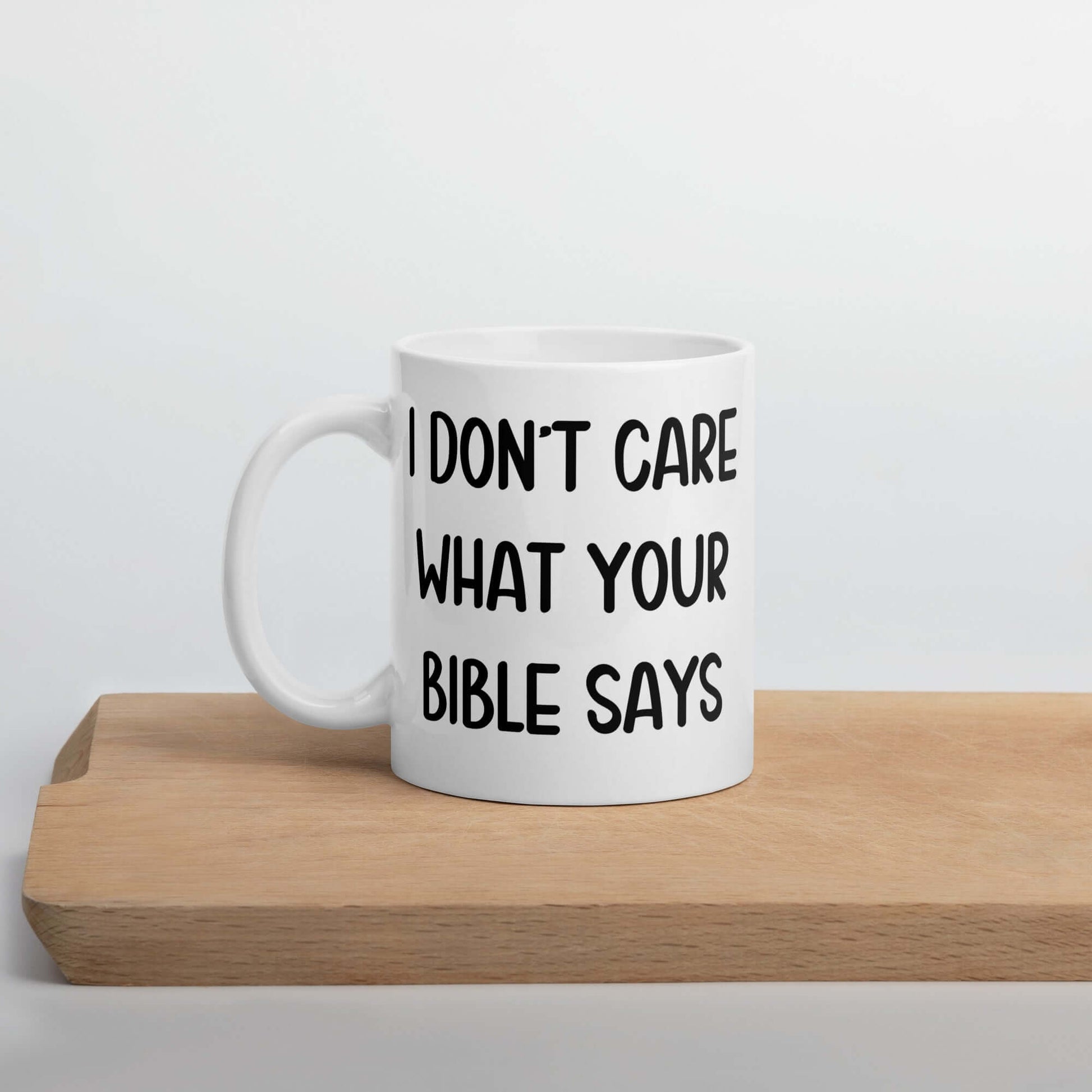 White ceramic mug with the words I don't care what your bible says printed on both sides.