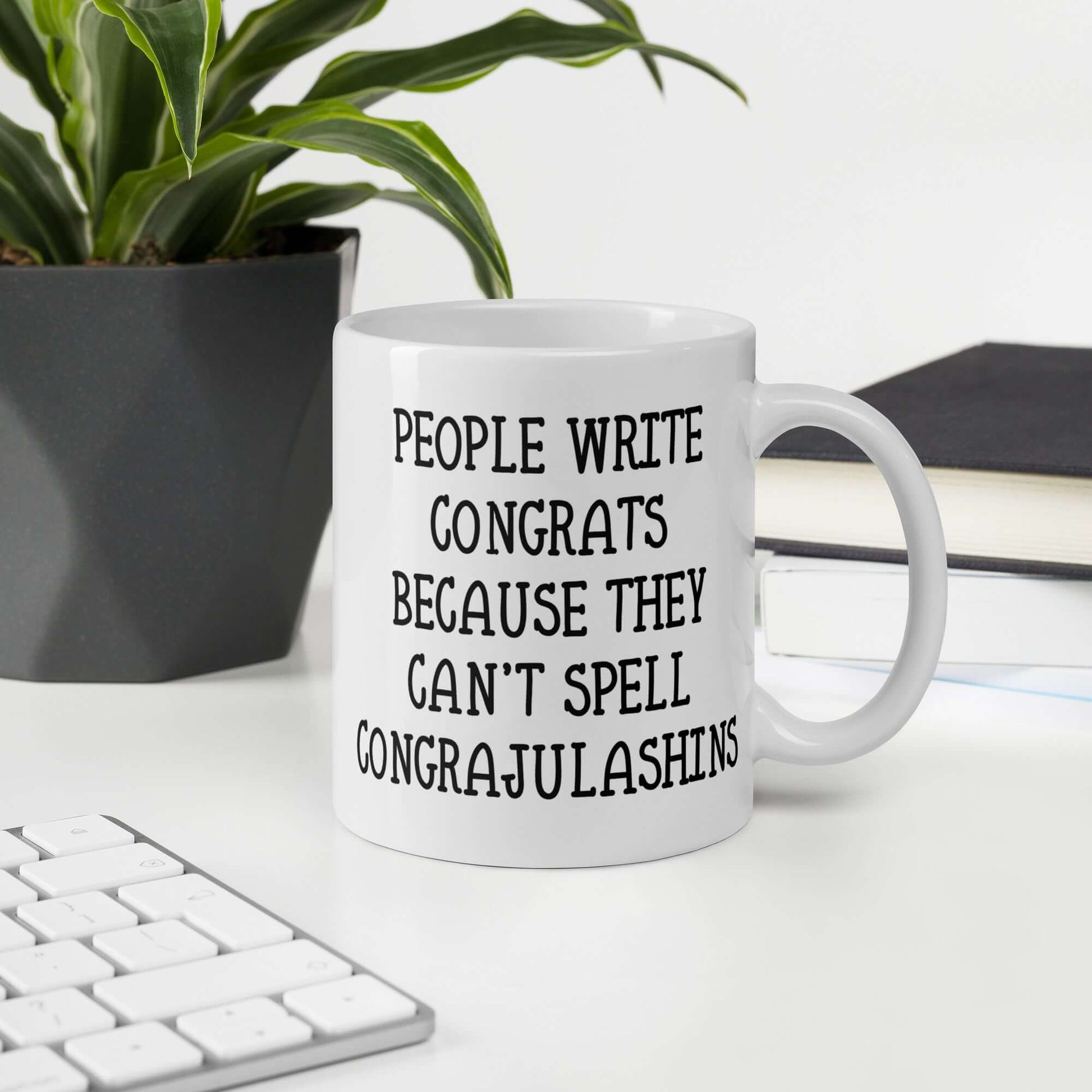 White ceramic mug with the words People write congrats because they can't spell congratulations printed on both sides. The word congratulations is intentionally misspelled.