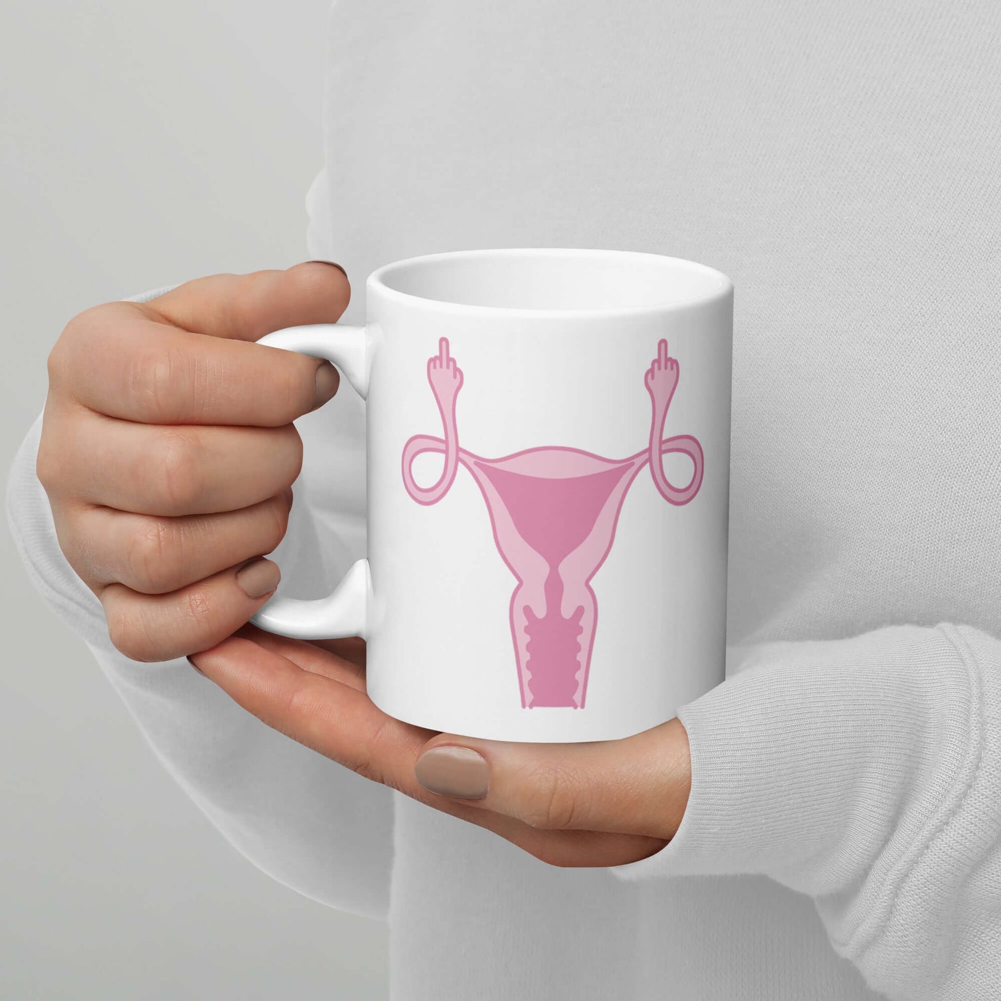 womans hands holding coffee mug with pink uterus flipping middle finger graphic printed on it by witticisms r us dot com