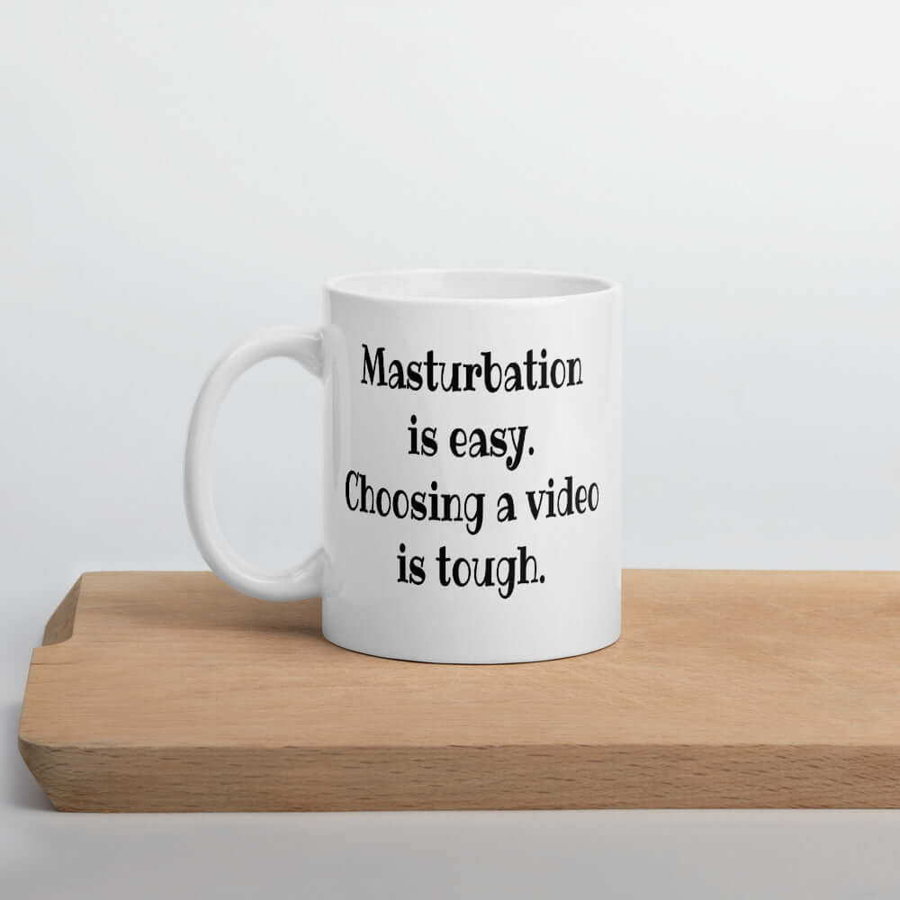 White ceramic coffee mug with the phrase Masturbation is easy, choosing a video is tough printed on both sides.