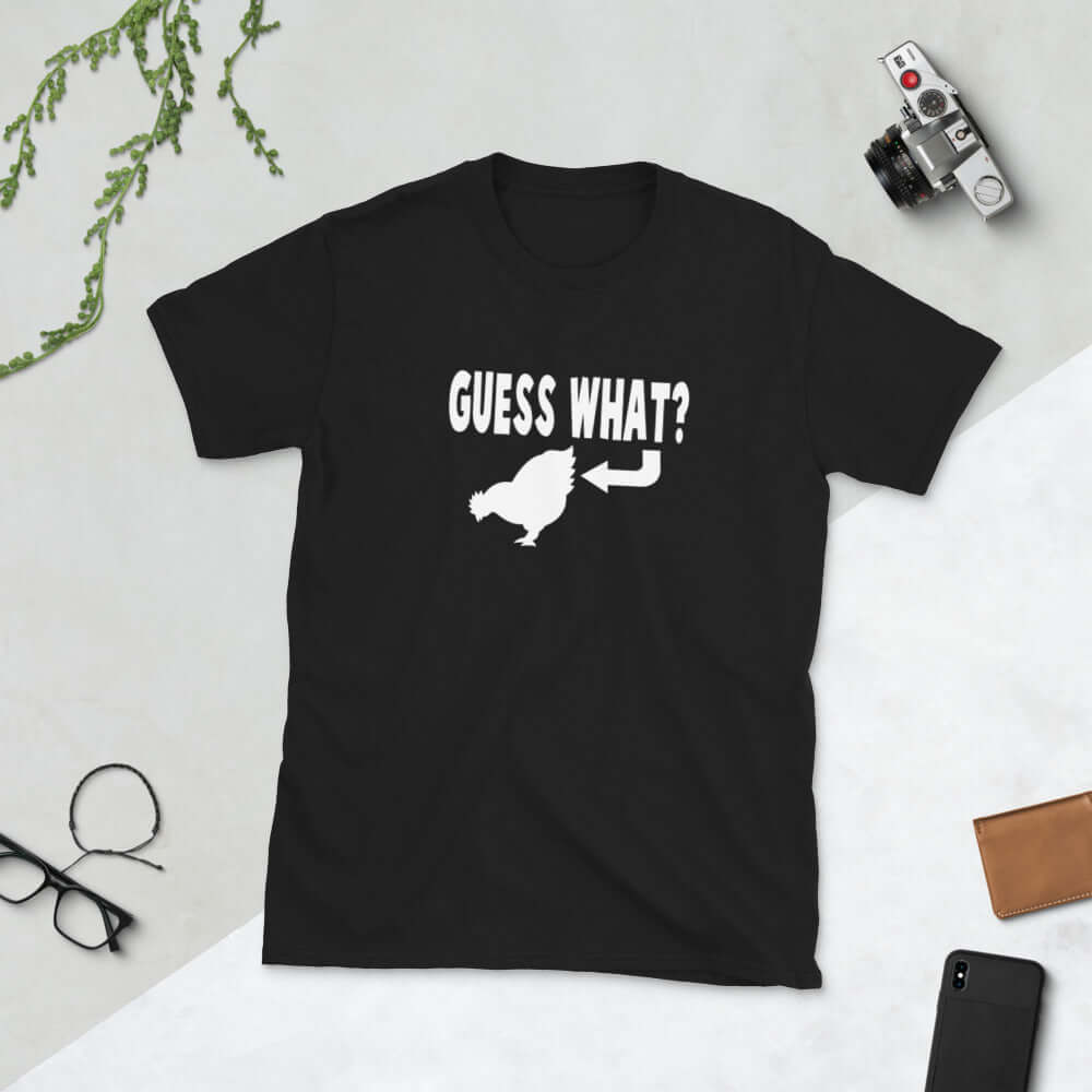 Black t-shirt with an image of a chicken and the words Guess what question mark. There is an arrow pointing to the chickens butt. The graphics are printed on the front of the shirt.