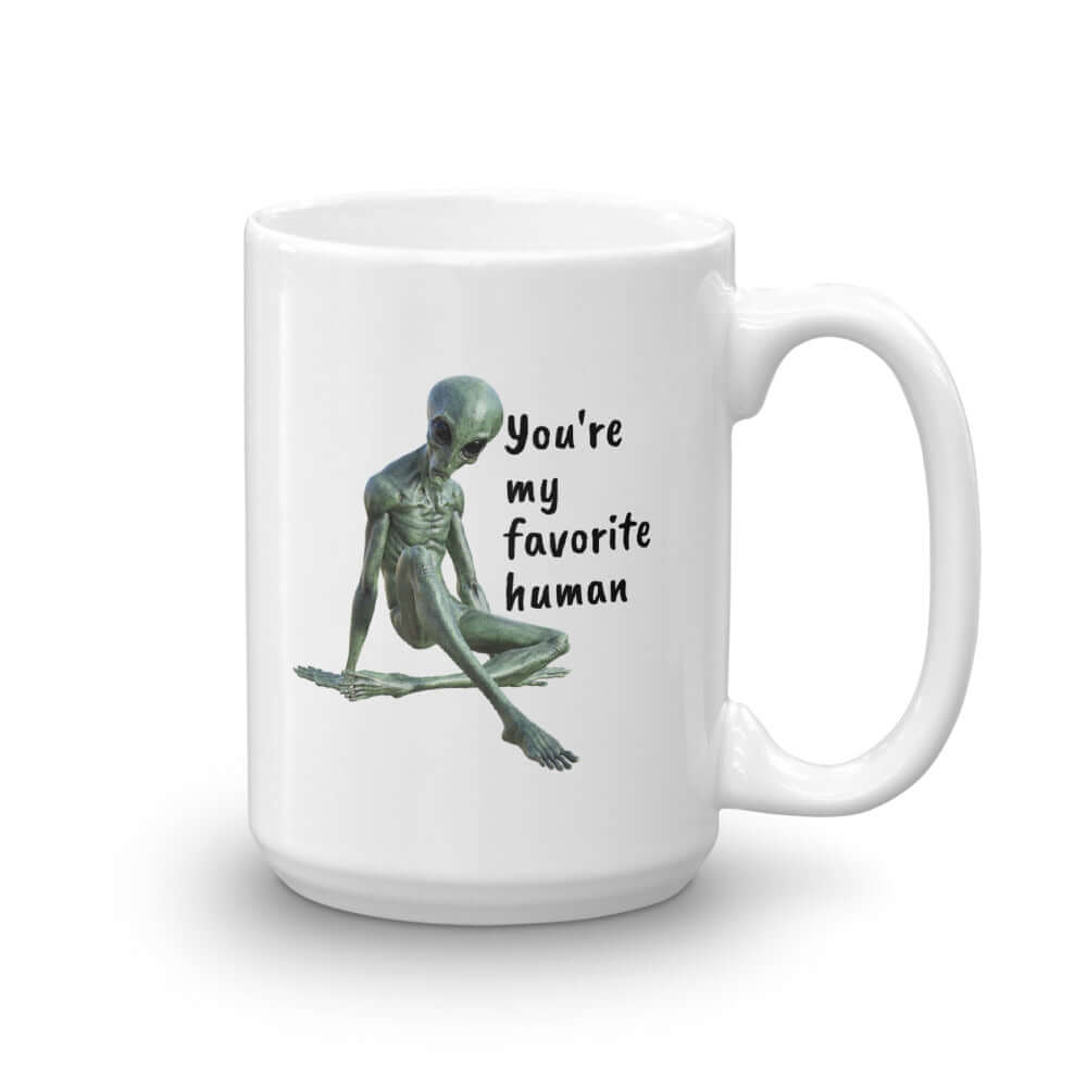 White ceramic coffee mug with funny image of an alien lounging and the words You're my favorite human printed on both sides of the mug.