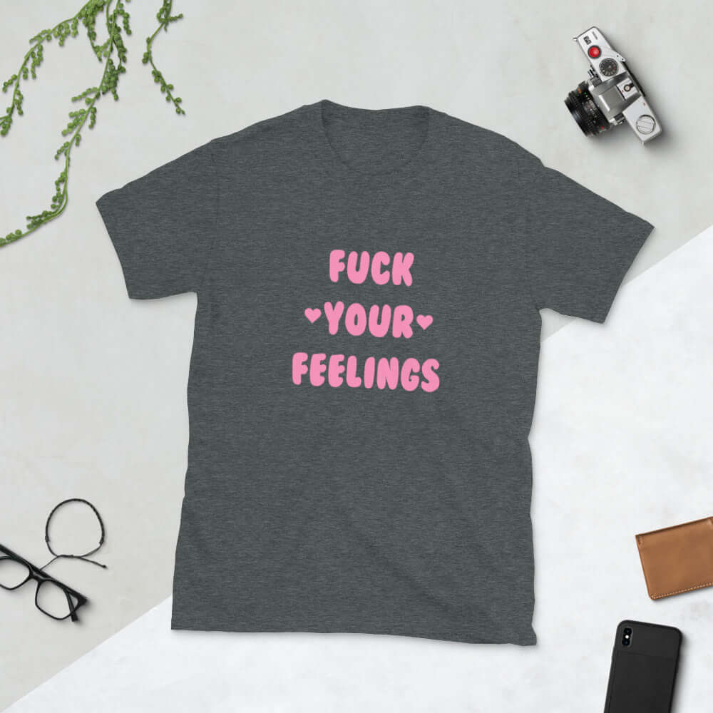 Dark grey t-shirt with the words Fuck your feelings printed on the front in pink. There are cute pink hearts next to the words.