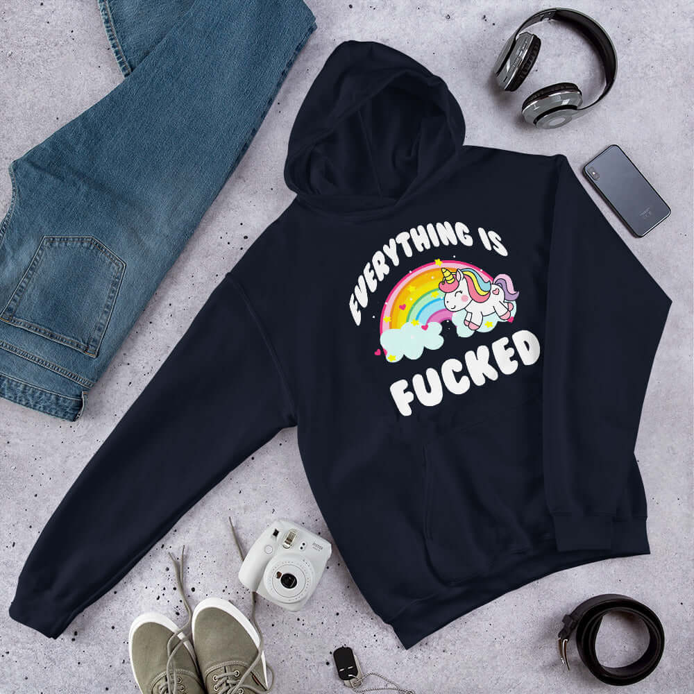 Navy blue hoodie sweatshirt with a graphic of a kawaii style unicorn and a pastel rainbow with the words Everything is fucked printed on the front.