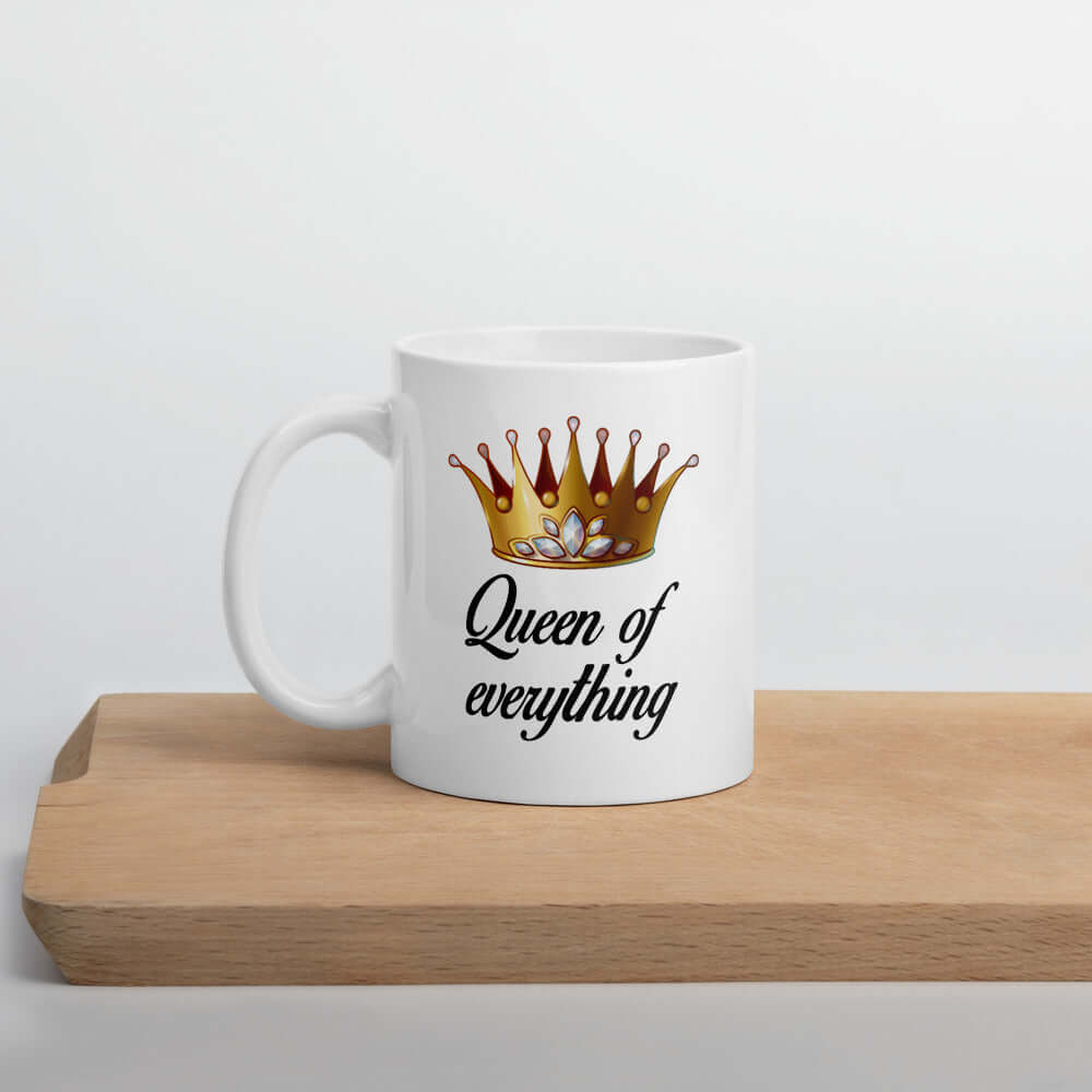 White ceramic coffee mug with an image of a crown and the phrase Queen of everything printed on both sides of the mug.