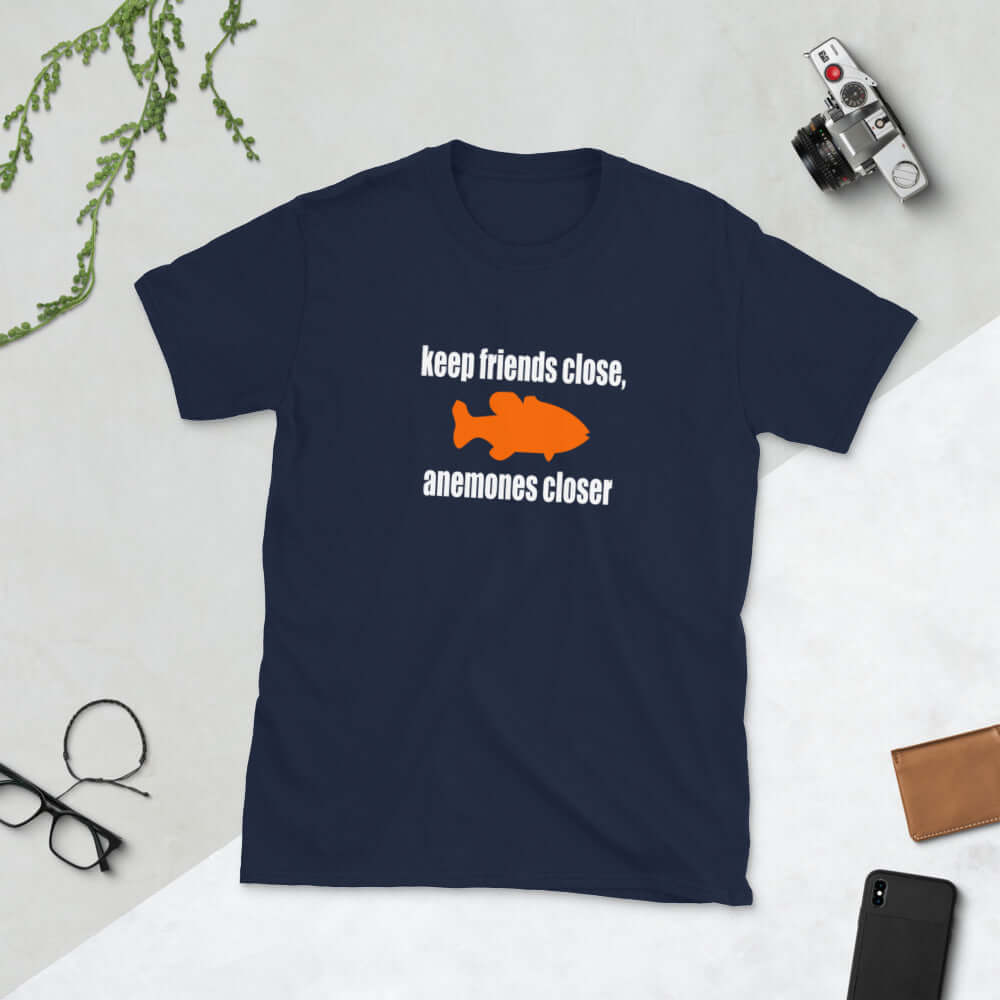 Navy blue t-shirt with the pun phrase Keep friends close, anemones closer with an image of an orange fish.