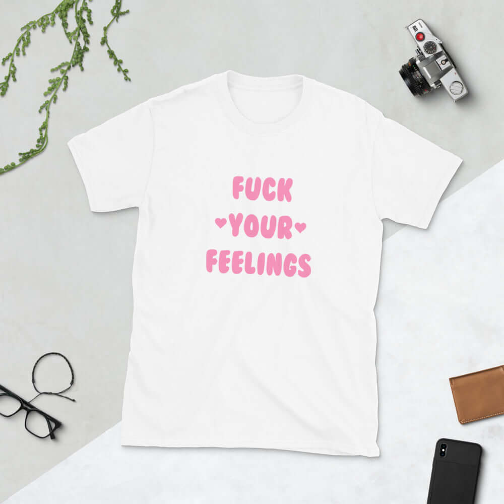 White t-shirt with the words Fuck your feelings printed on the front in pink. There are cute pink hearts next to the words.