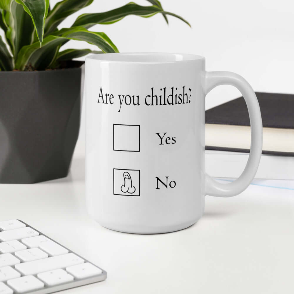 White ceramic coffee mug with the words Are you childish question mark. There are 2 check boxes to select Yes or No. There is a penis drawn inside of the No box. The graphics are printed on both sides of the mug.