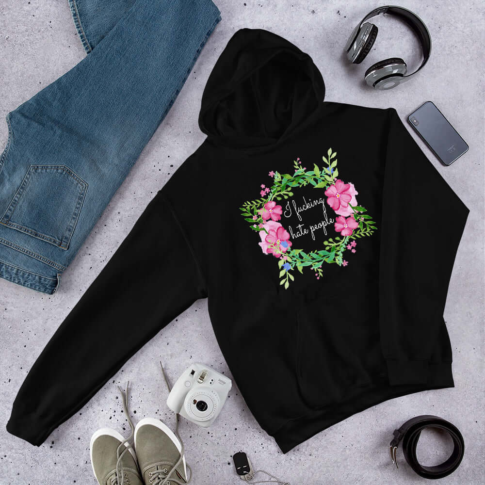 Black hooded sweatshirt with pink and green floral wreath image and the words I fucking hate people printed on the front.