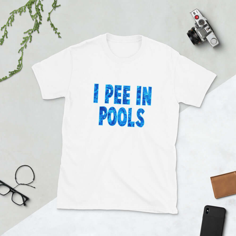 White t-shirt with the words I pee in pools printed in a font that looks like water. The graphics are printed on the front of the shirt.