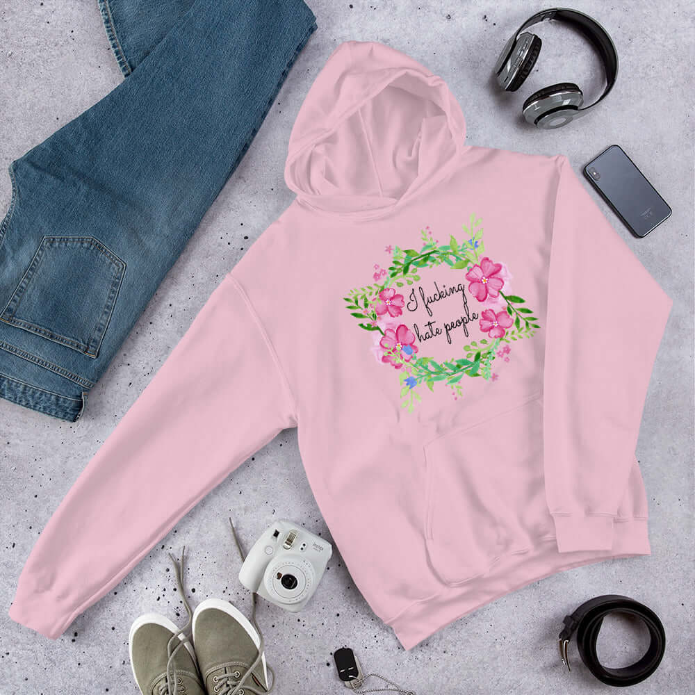 Light pink hooded sweatshirt with pink and green floral wreath image and the words I fucking hate people printed on the front.