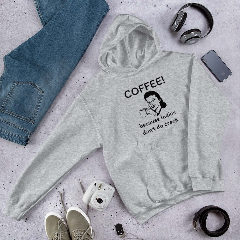 Light grey hoodie sweatshirt with an image of a retro woman holding a coffee mug with the phrase Coffee, because ladies don't do crack printed on the front.