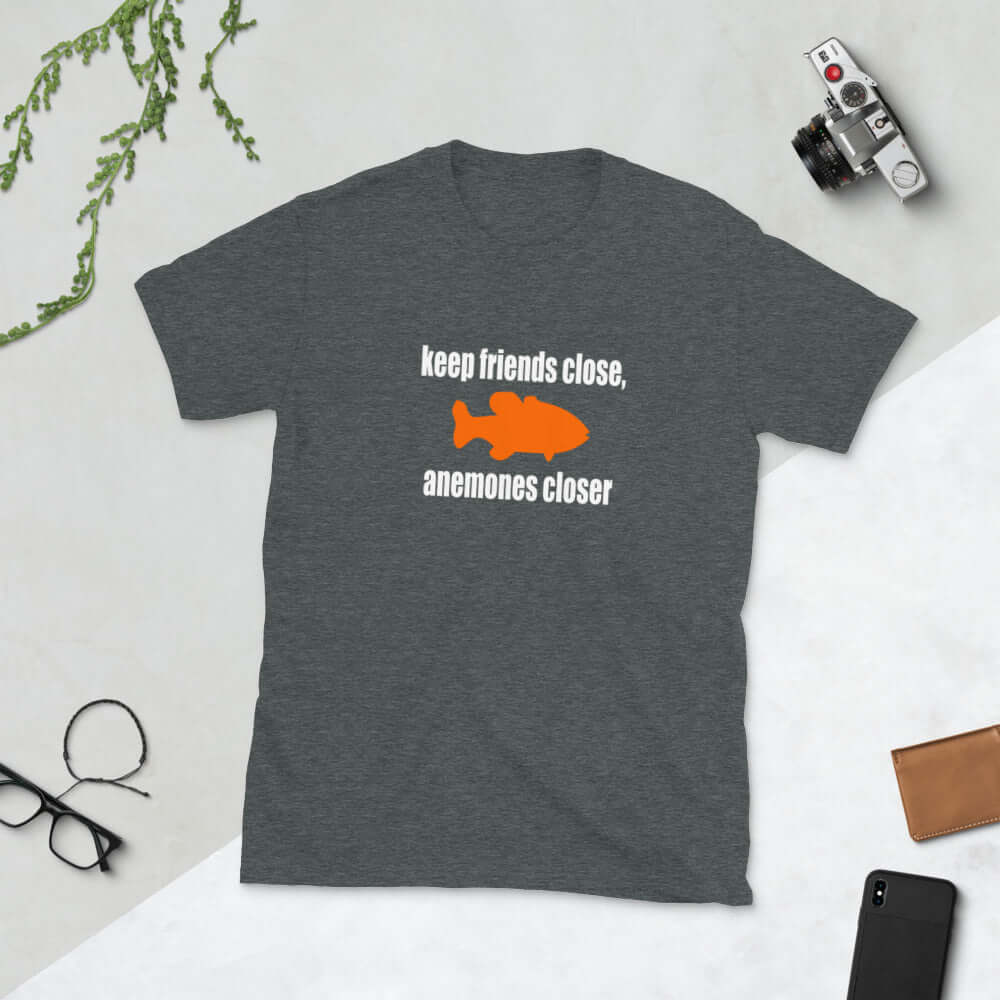 Dark heather grey t-shirt with the pun phrase Keep friends close, anemones closer with an image of an orange fish.